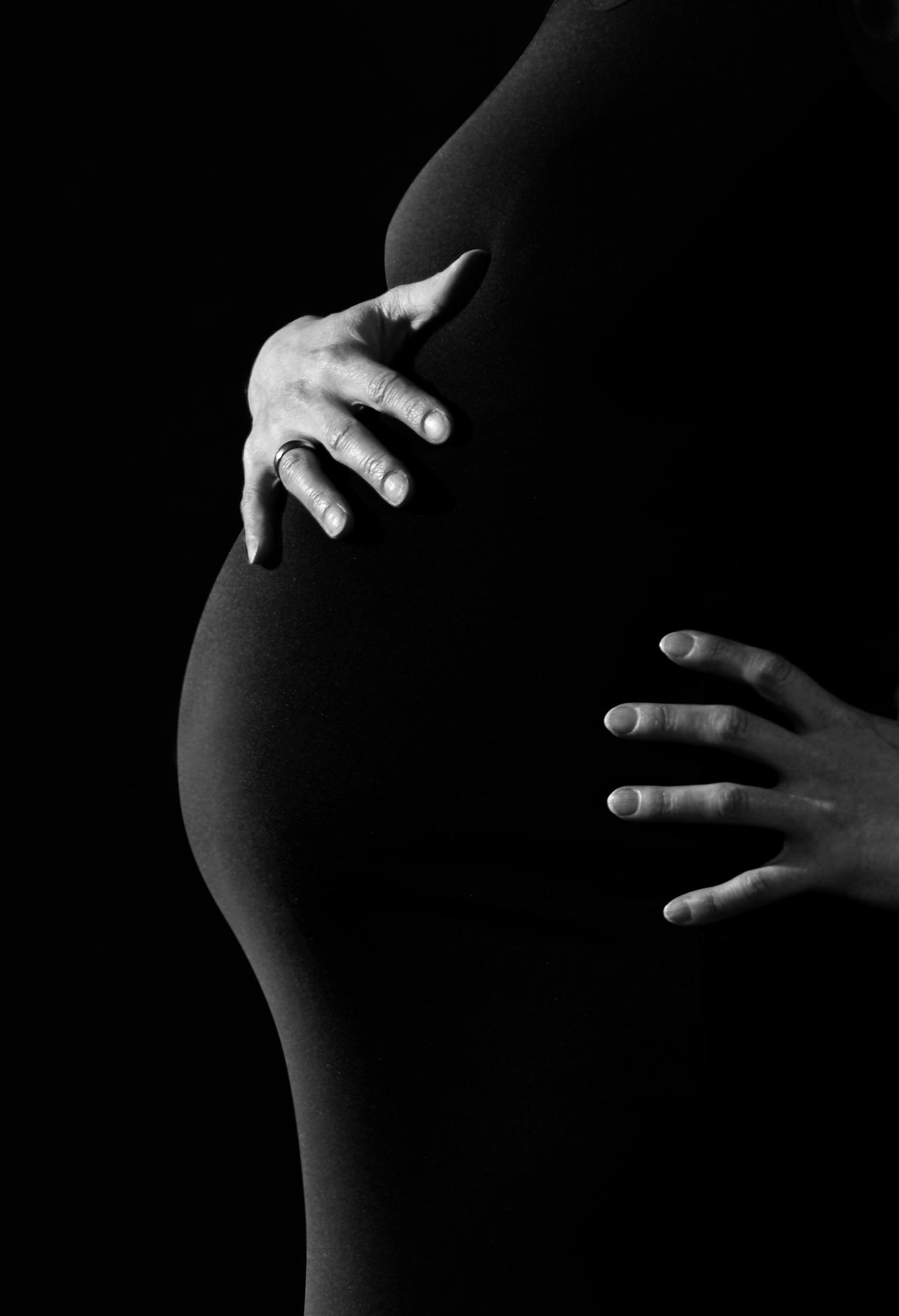 Une photo en noir et blanc d'une femme tenant son ventre de femme enceinte | Source : Pixabay sur Pexels