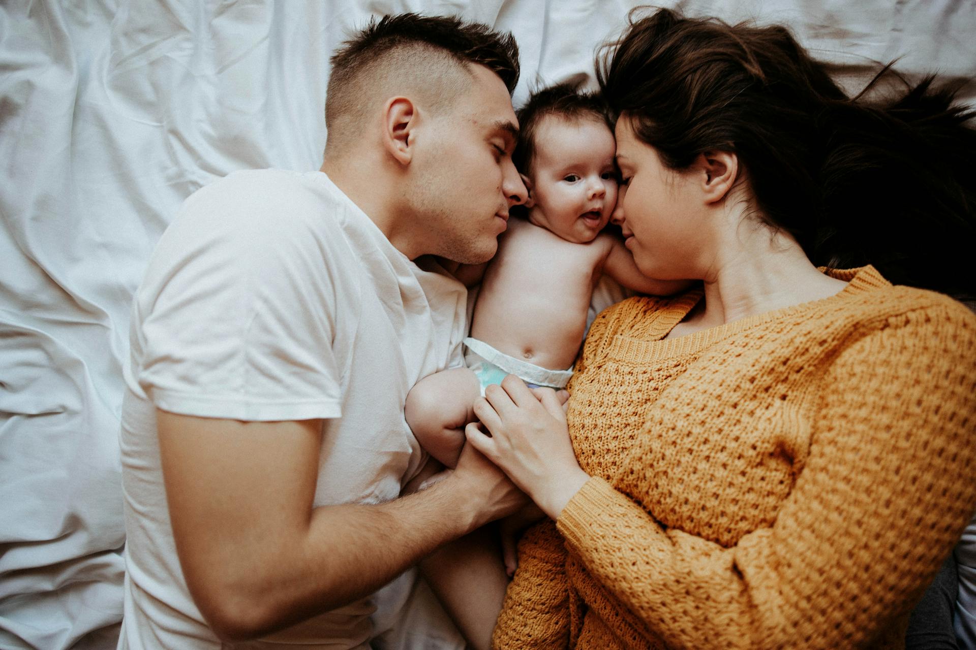 Un couple au lit avec un bébé | Source : Pexels