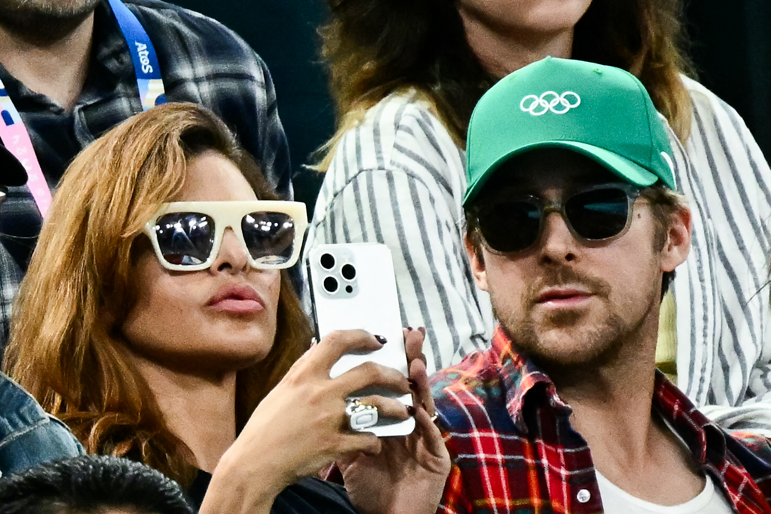 Eva Mendes tenant son téléphone à côté de Ryan Gosling tout en regardant la finale des barres asymétriques féminines à l'arène de Bercy lors des Jeux olympiques de Paris 2024, le 4 août 2024 | Source : Getty Images