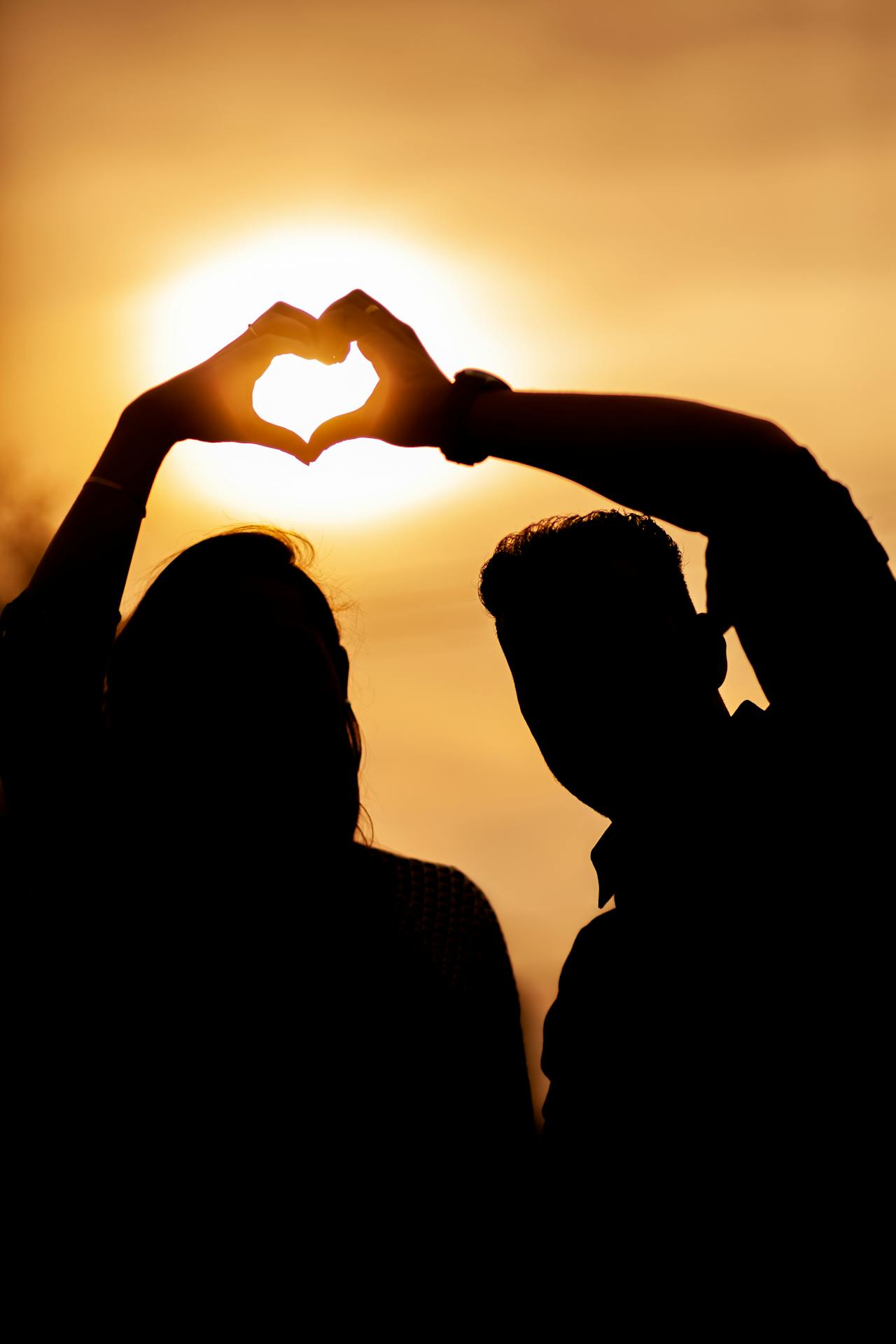 Silhouette d'un couple faisant le geste du cœur de la main | Source : Pexels