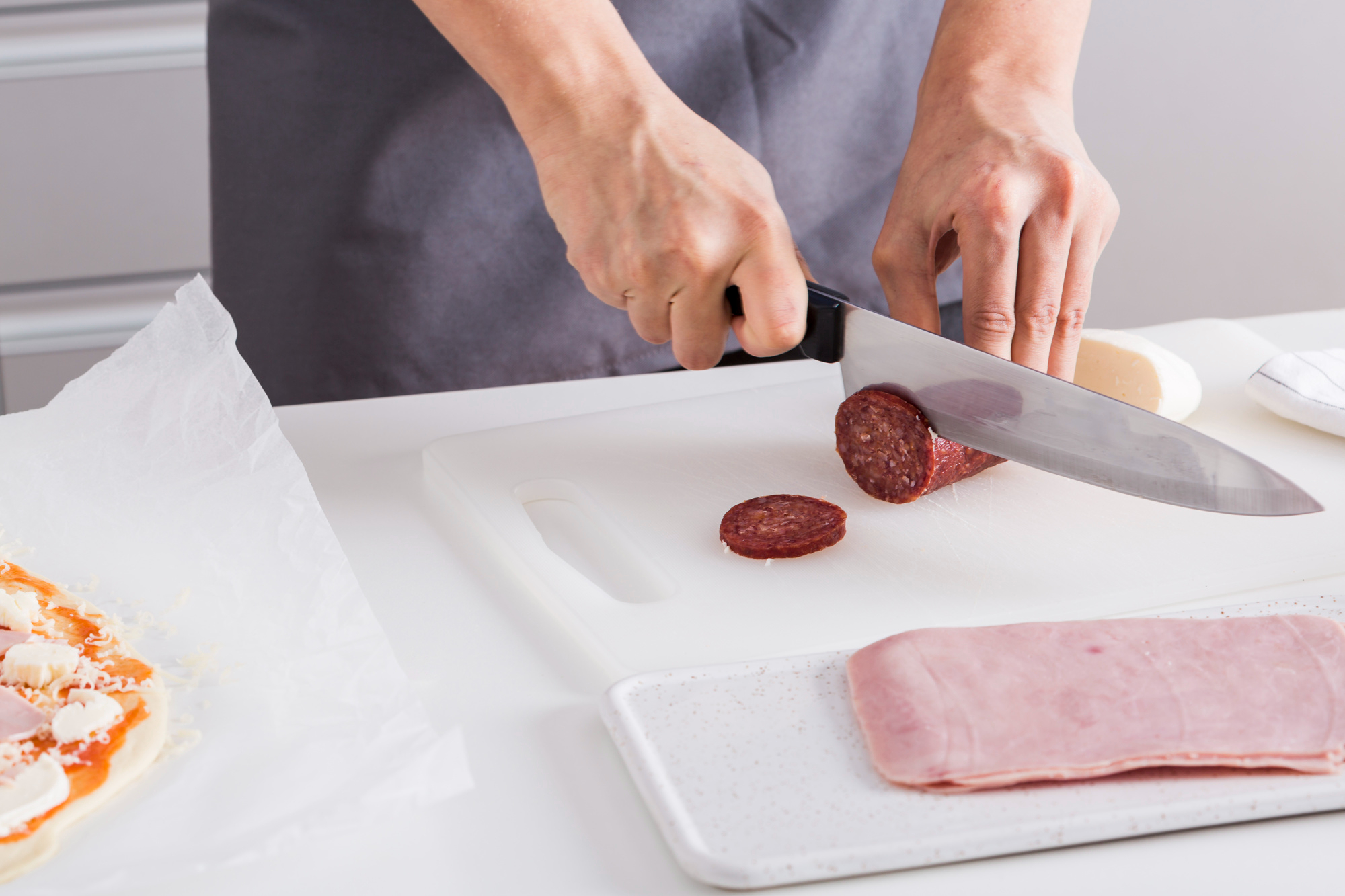 Une femme découpe des tranches de salami sur une planche à découper | Source : Freepik