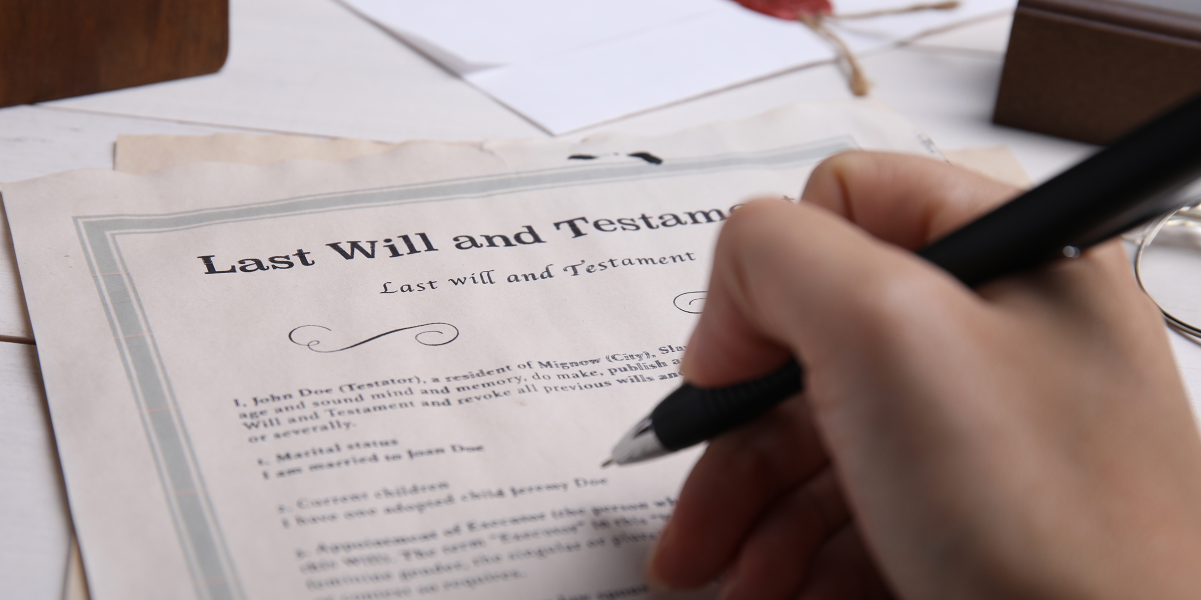 Une personne tenant un stylo au-dessus d'un testament | Source : Shutterstock