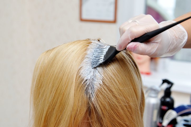 Coiffeur appliquant une teinture sur les cheveux d'une femme. | Photo : Getty Images