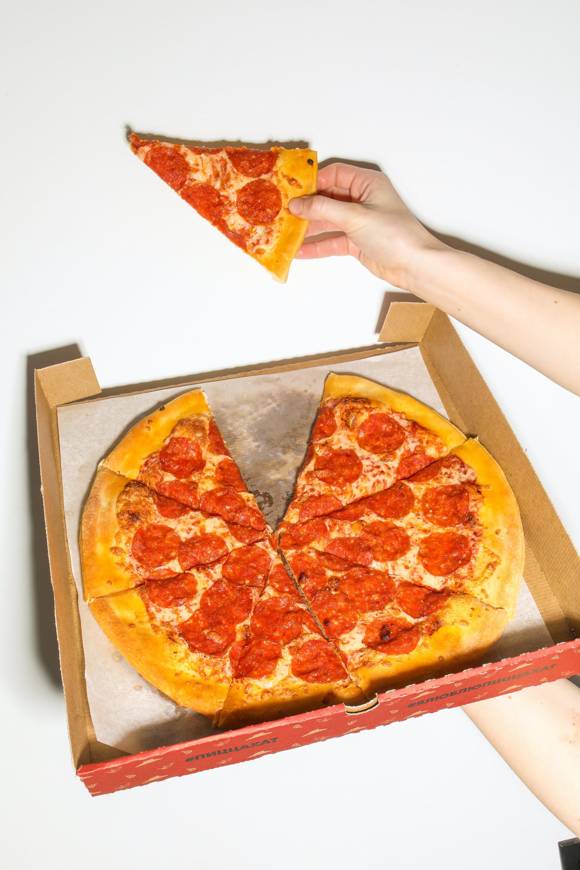 Une personne tenant une part de pizza et une boîte de pizza | Source : Pexels