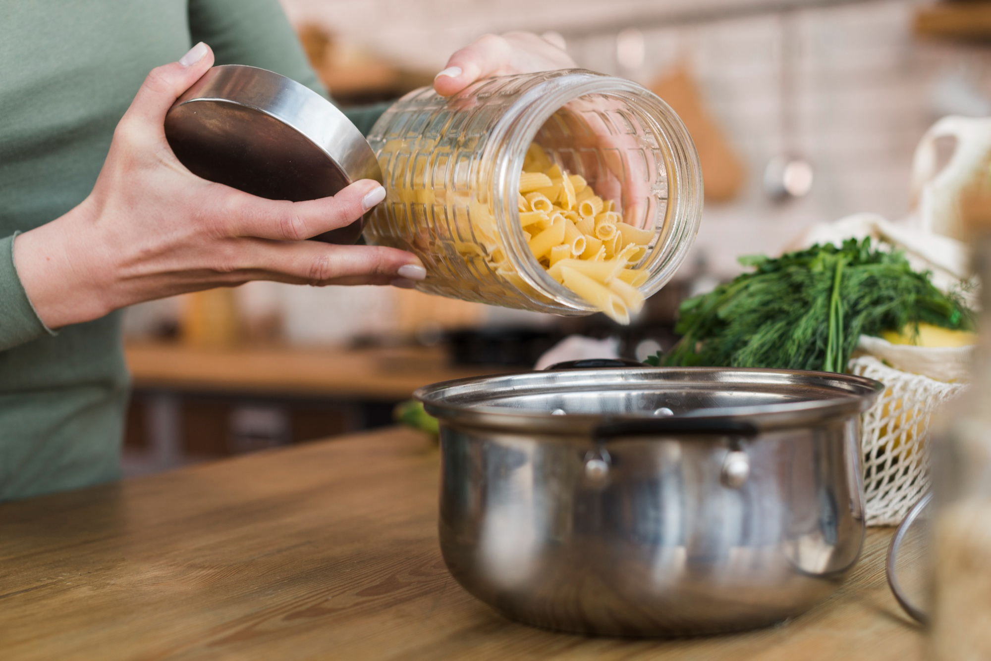 Une femme verse des pâtes crues dans une casserole | Source : Freepik