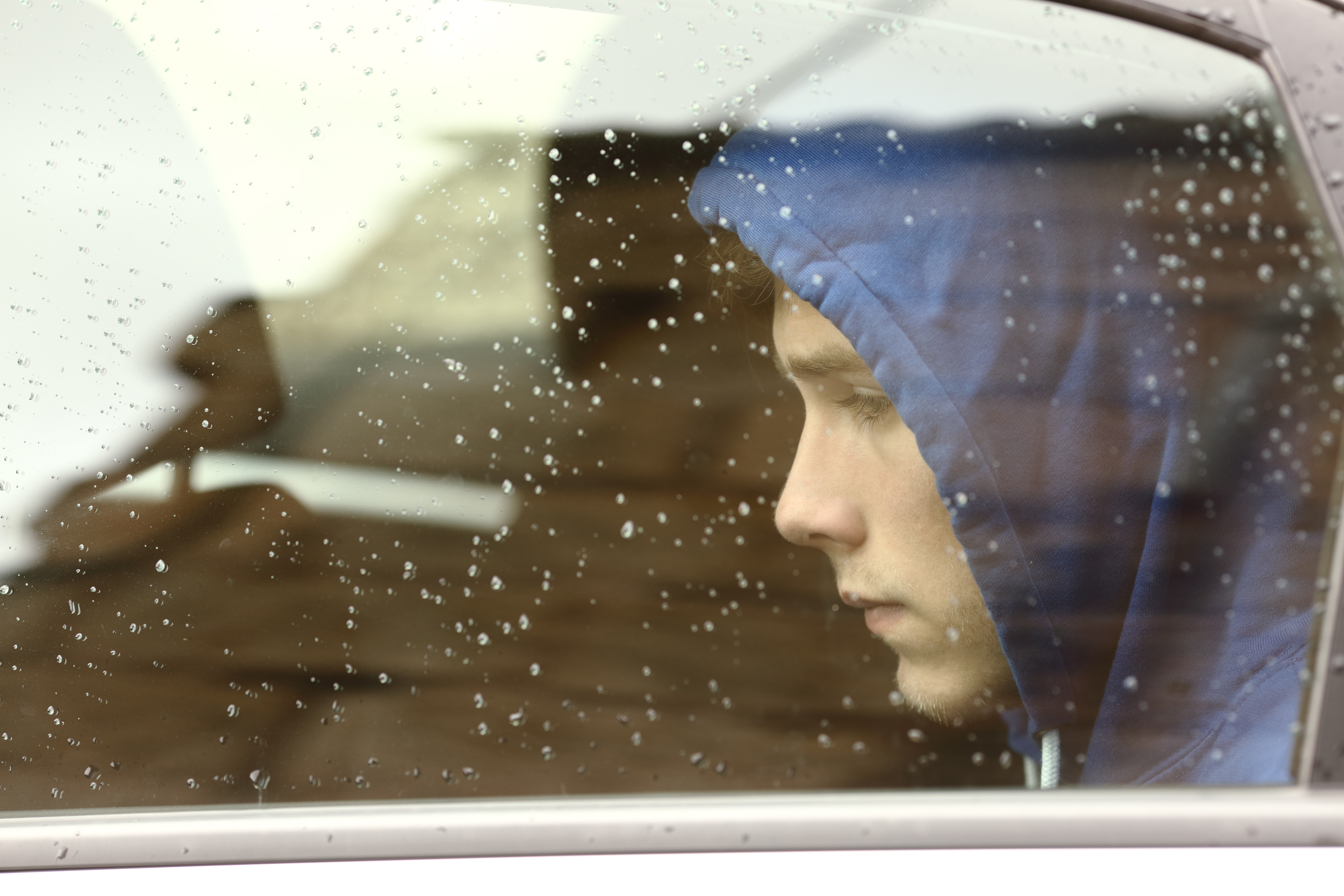 Un adolescent triste regarde par la fenêtre de la voiture | Source : Shutterstock