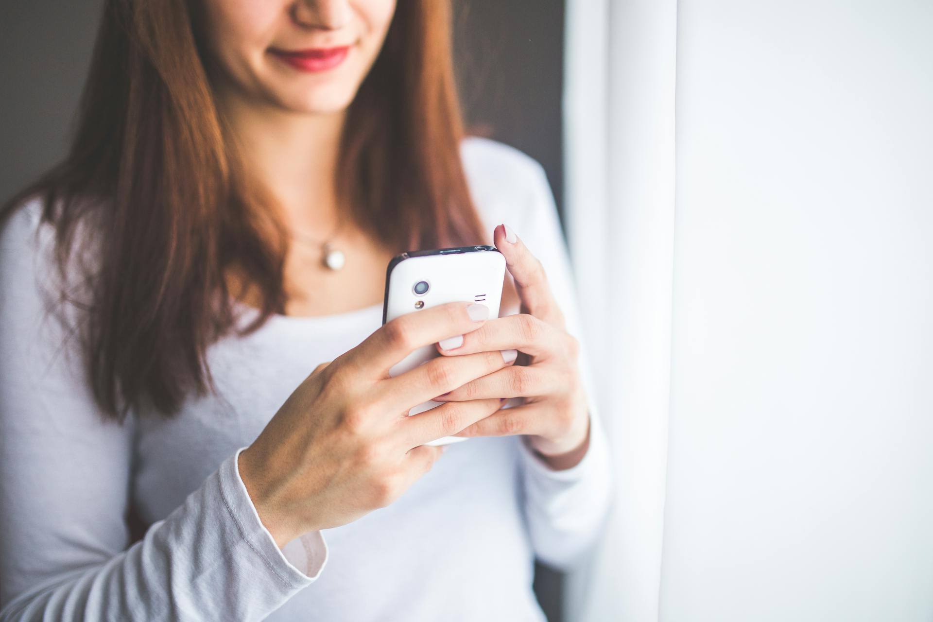 Une femme tenant un smartphone blanc | Source : Pexels