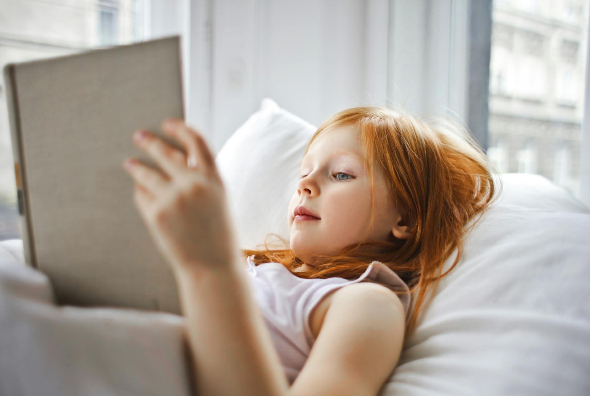 Une petite fille tenant un livre dans son lit | Source : Pexels