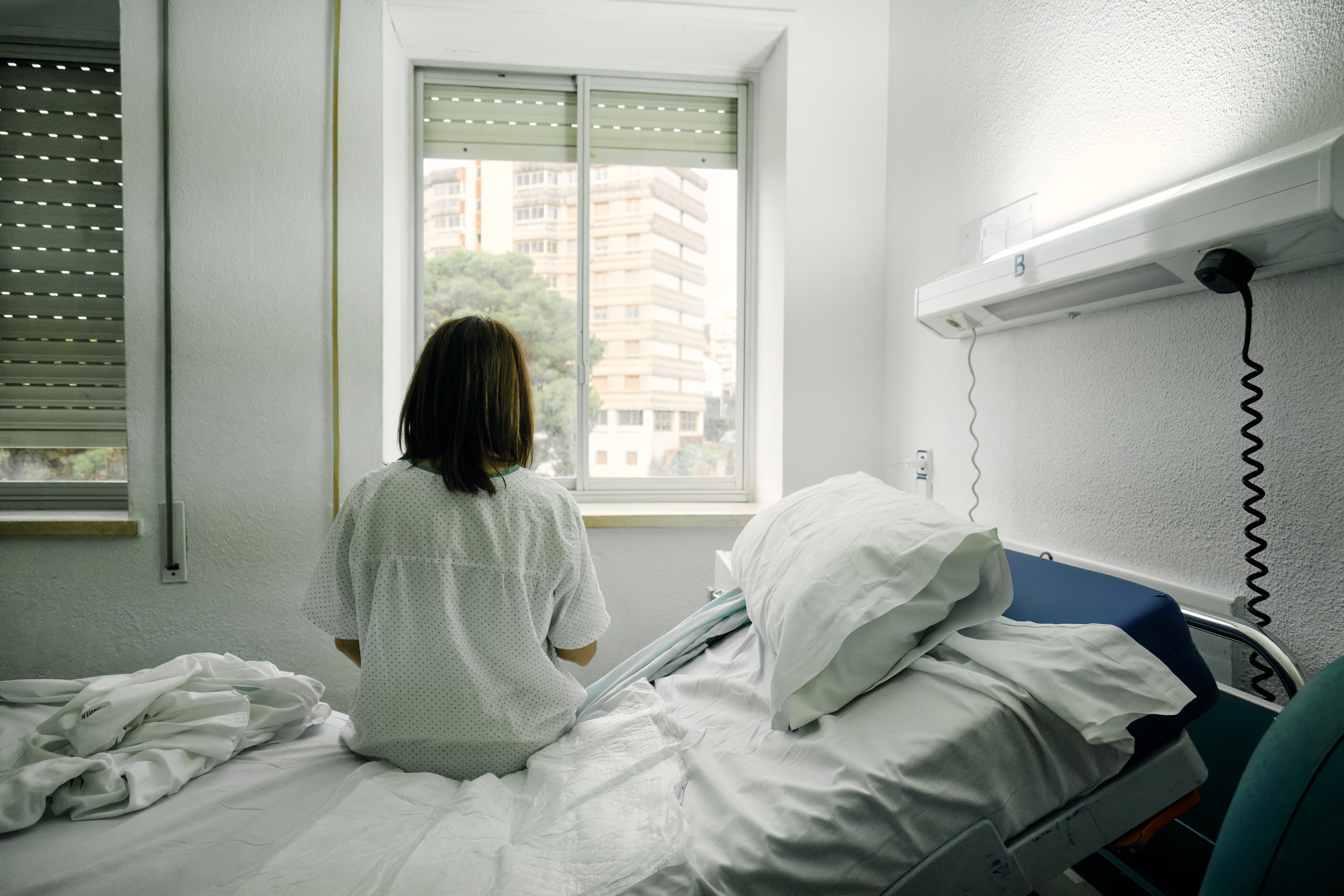 Vue de dos d'une femme assise sur un lit d'hôpital | Source : Getty Images