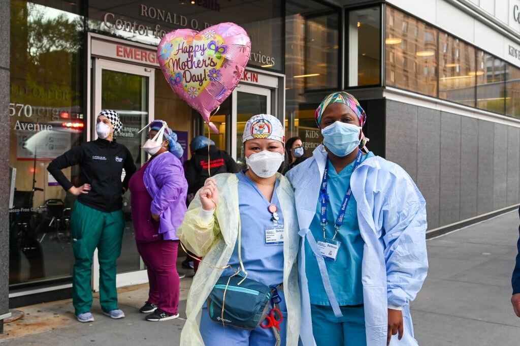 NEW YORK, NEW YORK - 10 MAI : Deux travailleurs médicaux posent pour une photo en tenant un ballon "Happy Mother's Day" lors de la pandémie COVID-19 le 10 mai 2020 à New York. | Photo : Getty Images
