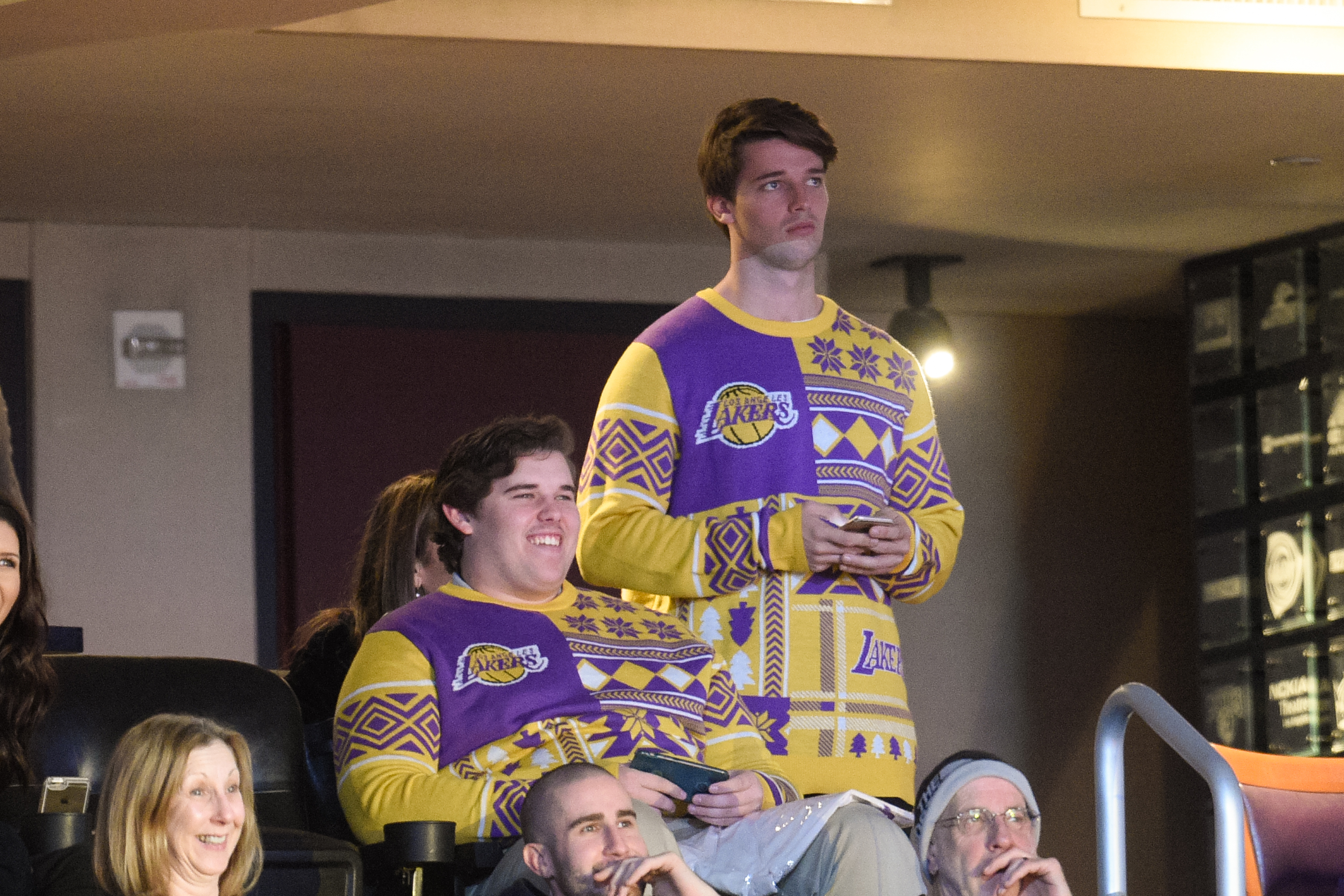 Christopher regarde le match des Lakers avec son frère Patrick au Staples Center de Los Angeles en décembre 2015. Vêtu d'un audacieux pull de vacances violet et jaune sur le thème des Lakers, Christopher est vu assis et souriant, ses cheveux soigneusement peignés et son cadre notablement plus fourni à l'époque.