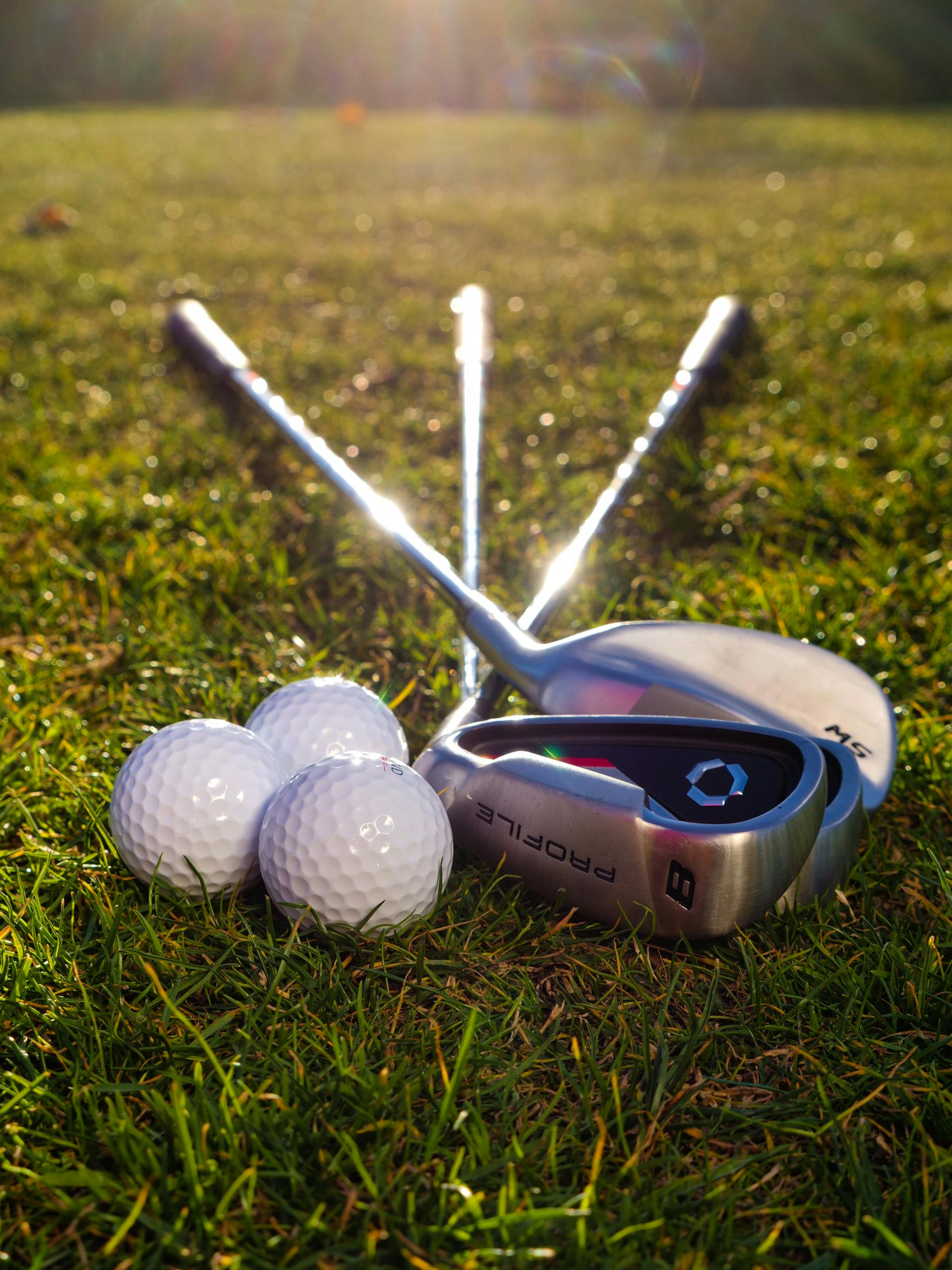 Des balles et des clubs de golf posés sur l'herbe | Source : Pexels