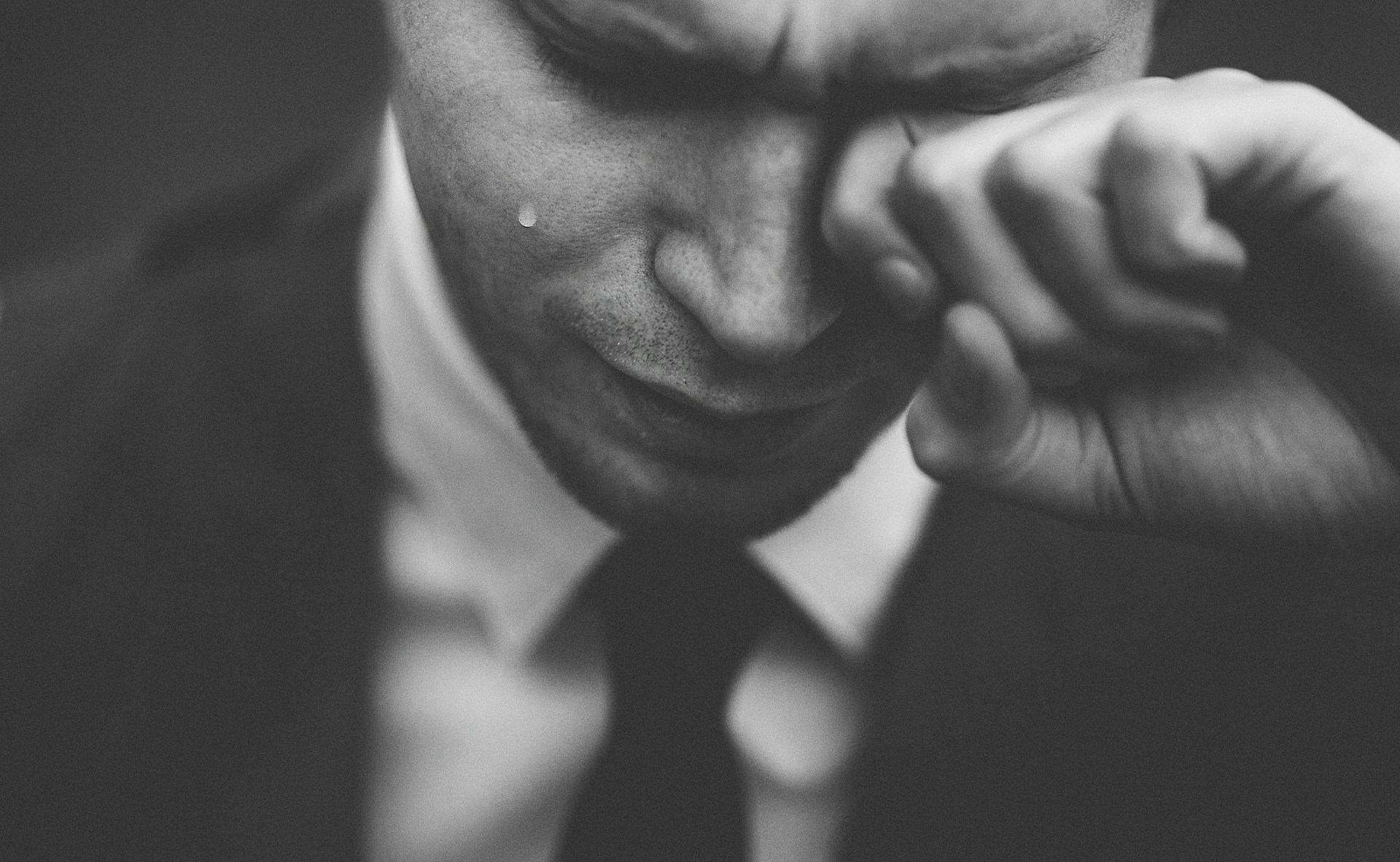 Un homme essuie les larmes de ses yeux | Source : Unsplash