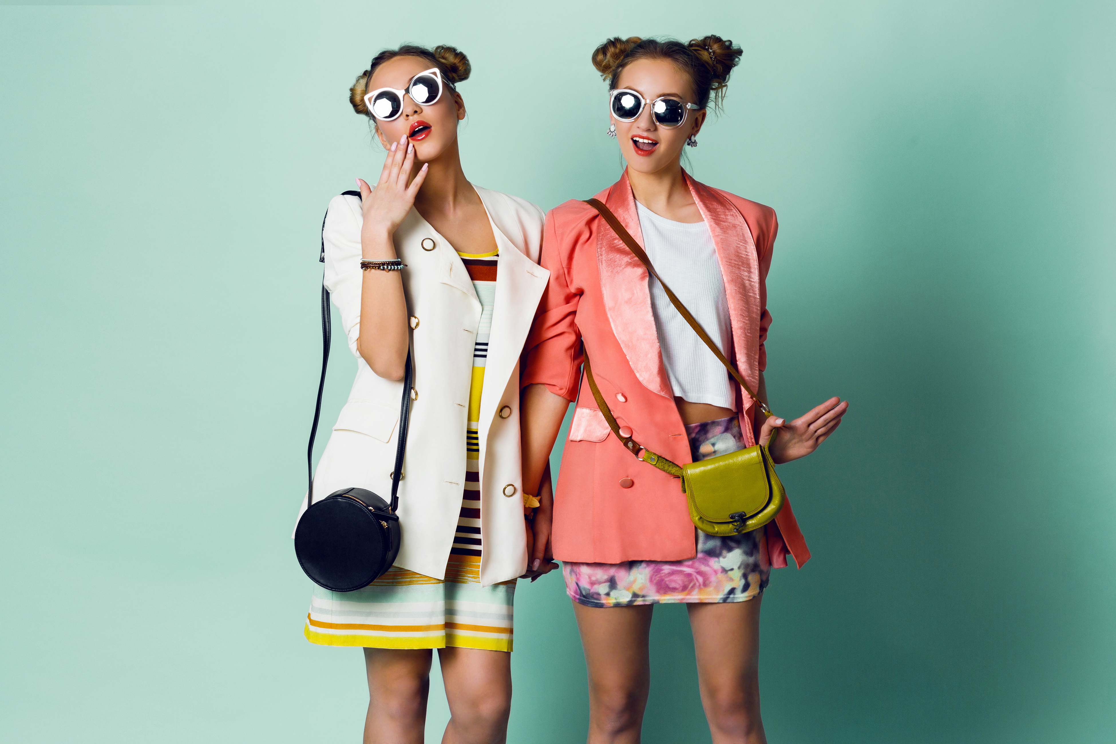 Deux sœurs avec des coiffures à cornes portant des vestes élégantes et des lunettes de soleil funky | Source : Shutterstock