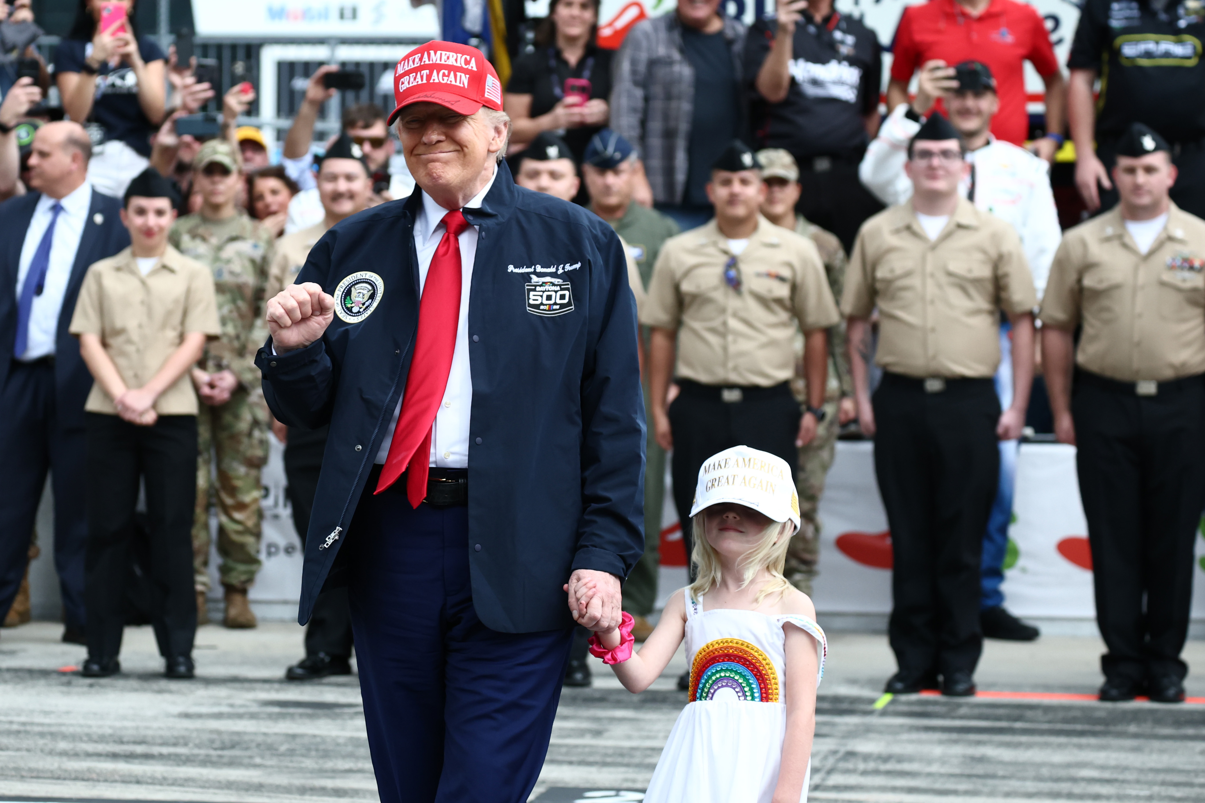 Le président américain Donald Trump et sa petite-fille Carolina se tiennent sur la grille pendant les cérémonies d'avant-course avant la NASCAR Cup Series Daytona 500 au Daytona International Speedway, le 16 février 2025, à Daytona Beach, en Floride | Source : Getty Images