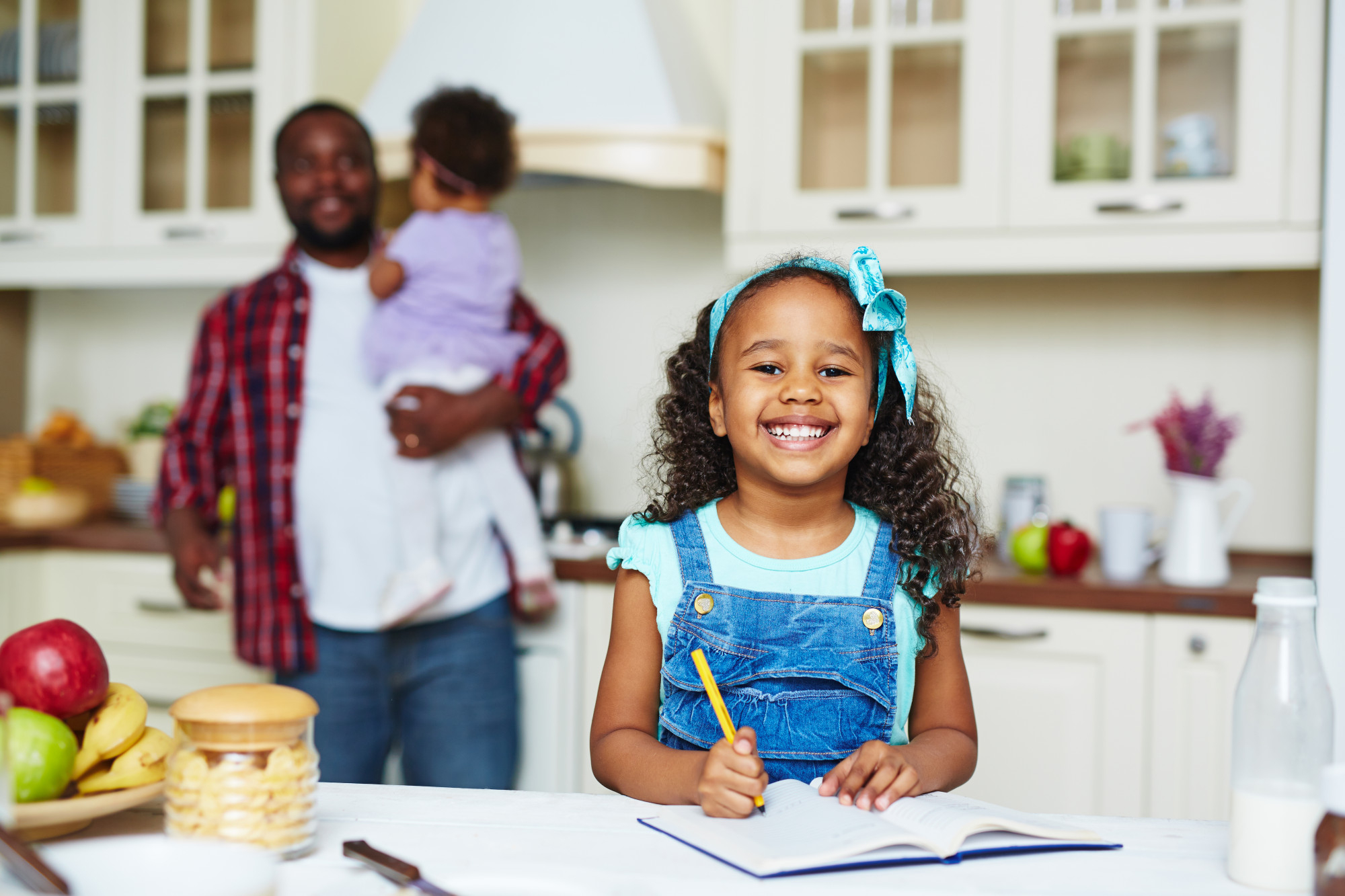 Un père portant sa fille pendant que l'autre fait ses devoirs | Source : Freepik