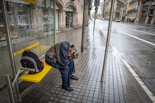 Un homme s'abritant de la pluie à un arrêt de bus de la Via Laietana pendant la crise de confinement du Coronavirus (COVID-19). | Photo : Getty Images.