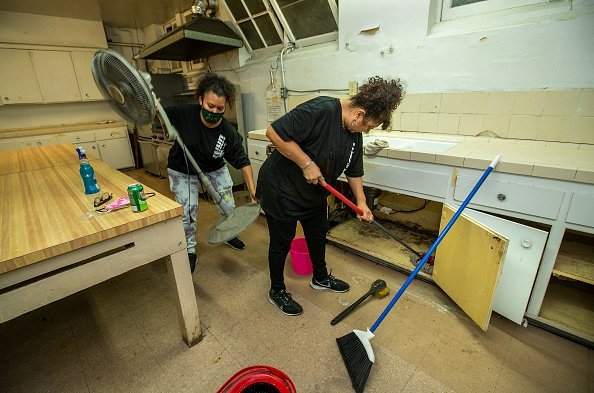 Des femmes qui néttoient des placars de cuisine. | Photo : Getty Images
