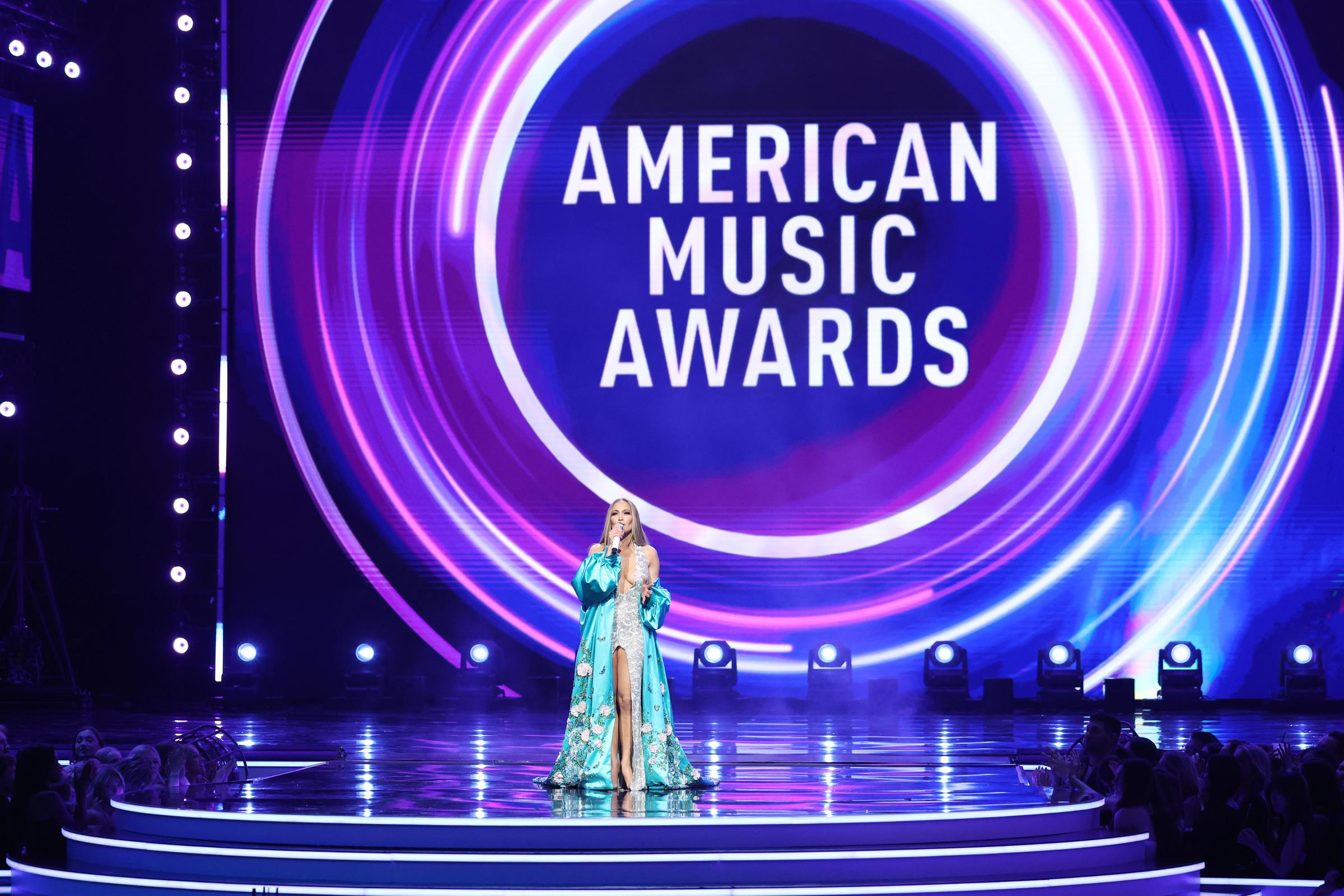 Jennifer Lopez clôt son moment sur scène aux American Music Awards, debout sous l'imposant logo de l'événement.