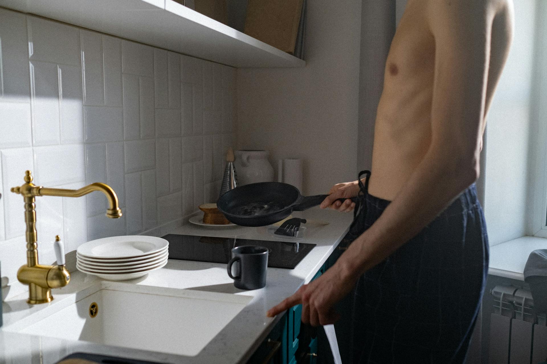 Un homme torse nu debout près d'un évier de cuisine | Source : Pexels