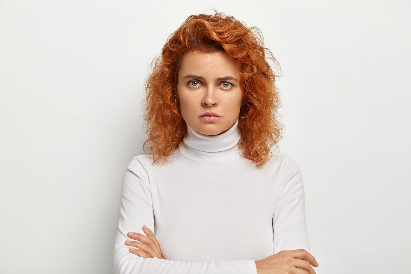 Une femme qui fronce les sourcils avec les bras croisés ⏐ Source : Freepik