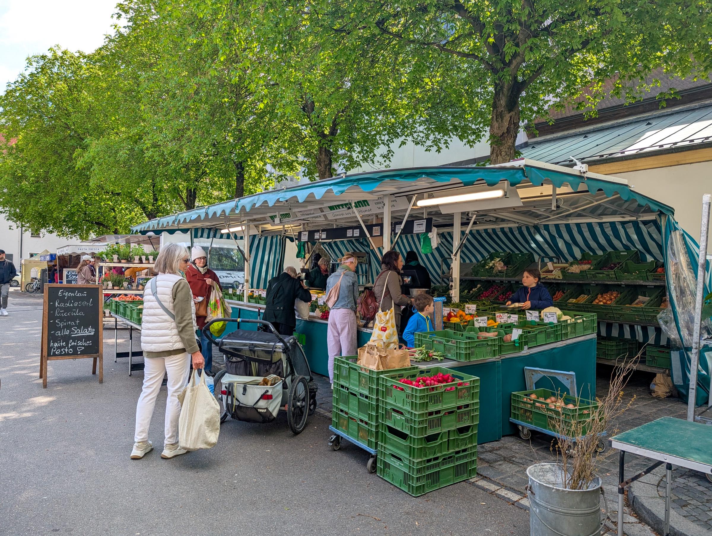 Les clients achètent des légumes frais, des fruits et des herbes aromatiques sur un marché de fruits et légumes en plein air | Source : Getty Images