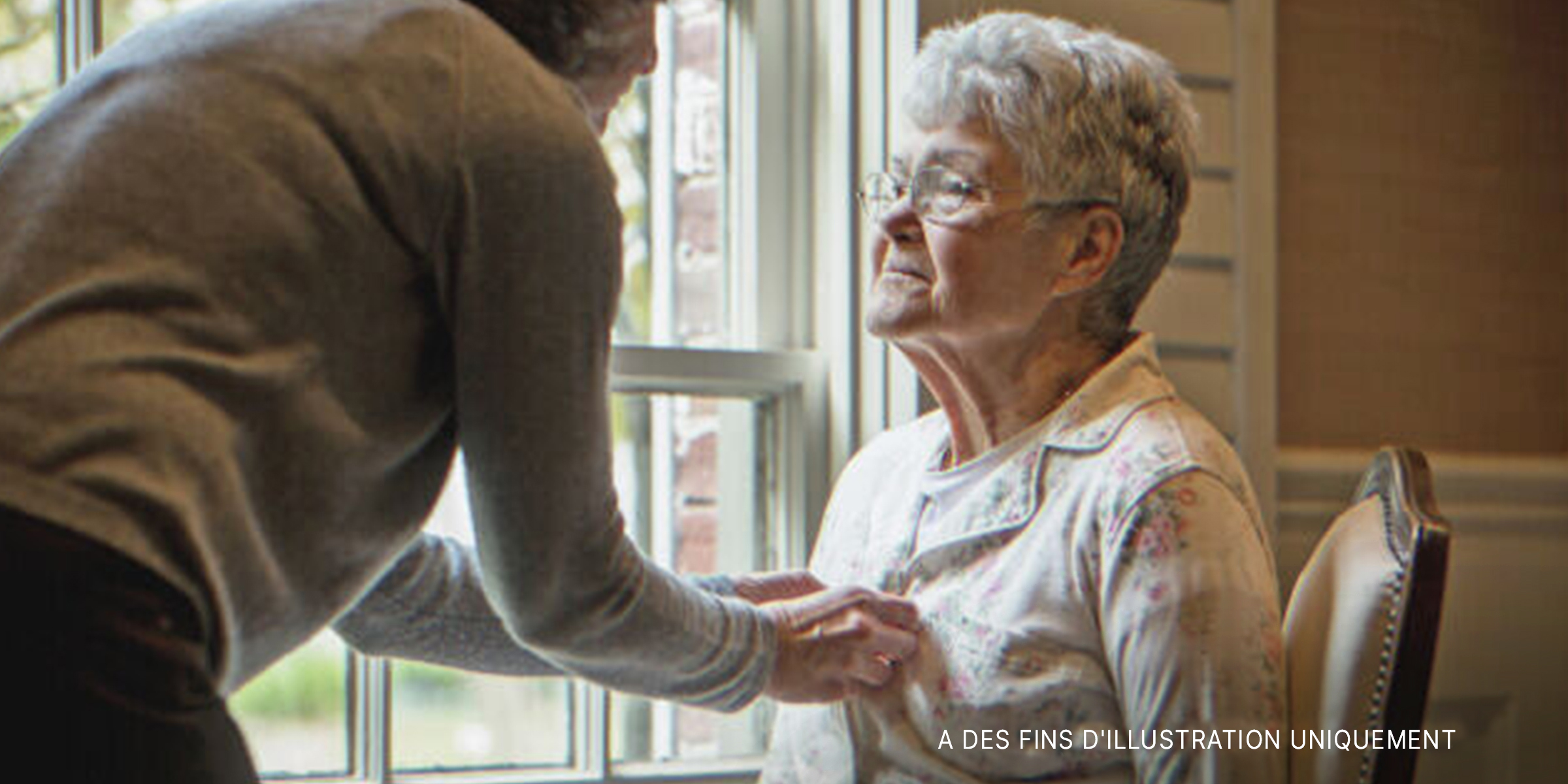 Une vieille dame assise pendant qu'une jeune femme l'aide. | Source : Getty Images