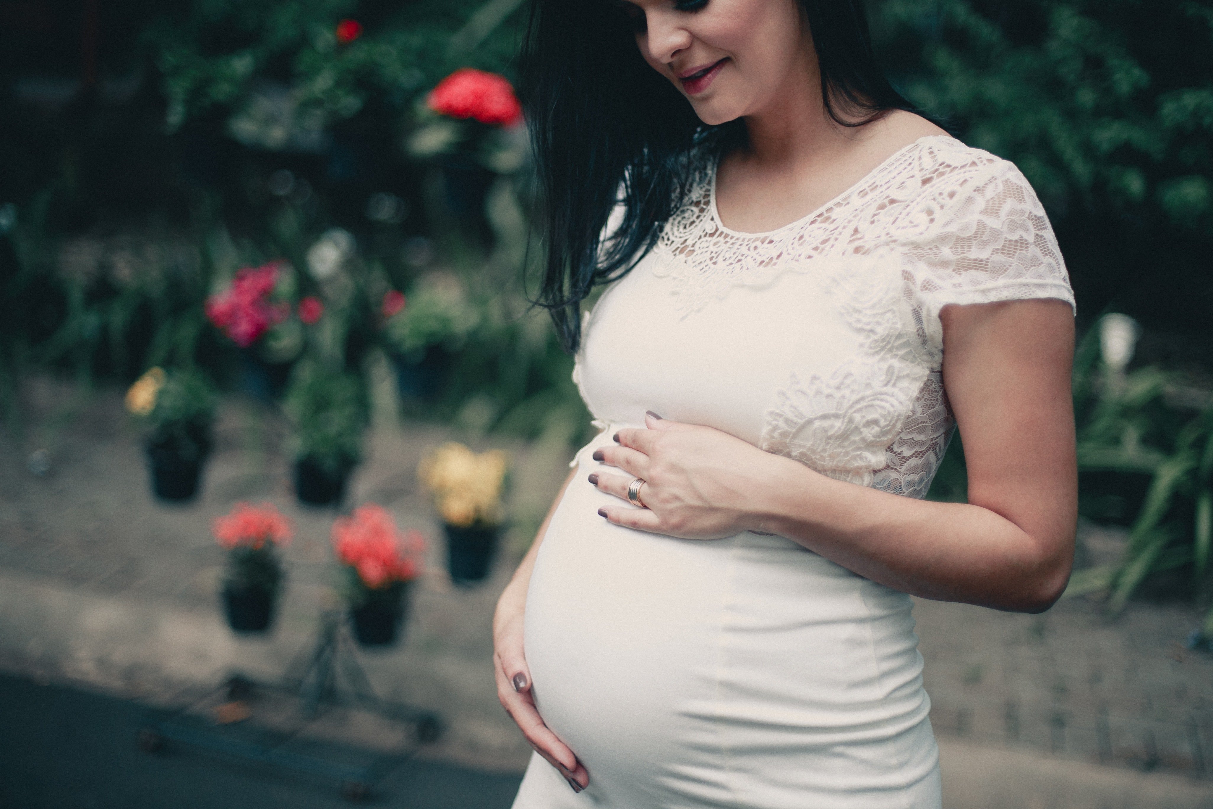 Photo en gros plan d'une femme enceinte portant une robe blanche et se tenant le ventre | Source : Pexels
