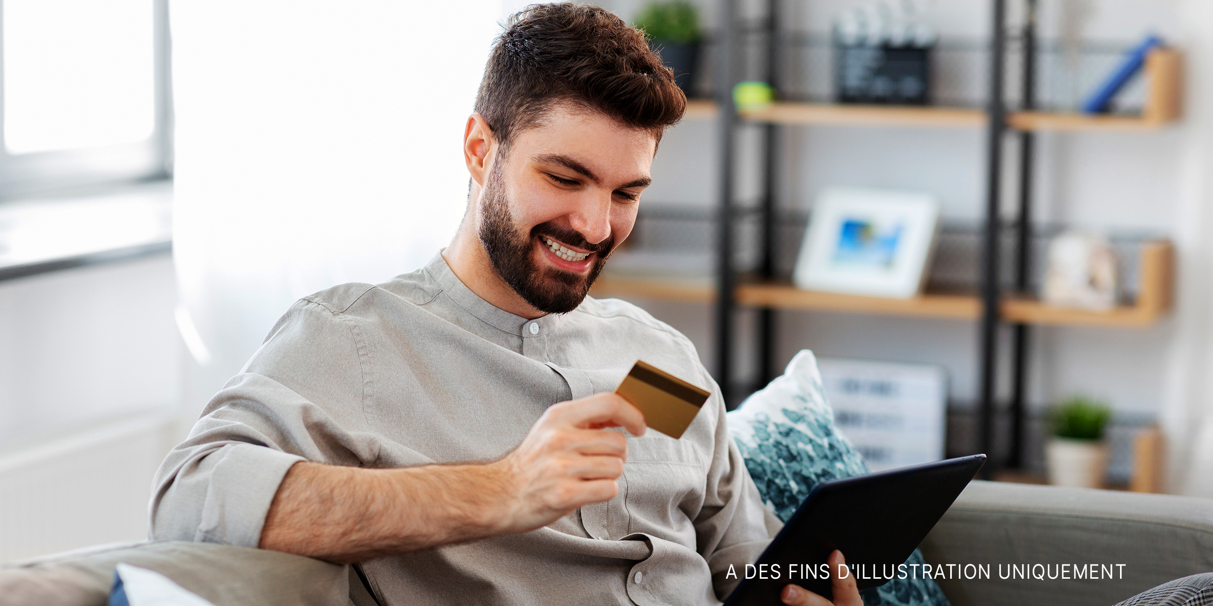 Un homme souriant tout en tenant une carte avec un ordinateur portable à la main | Source : Shutterstock