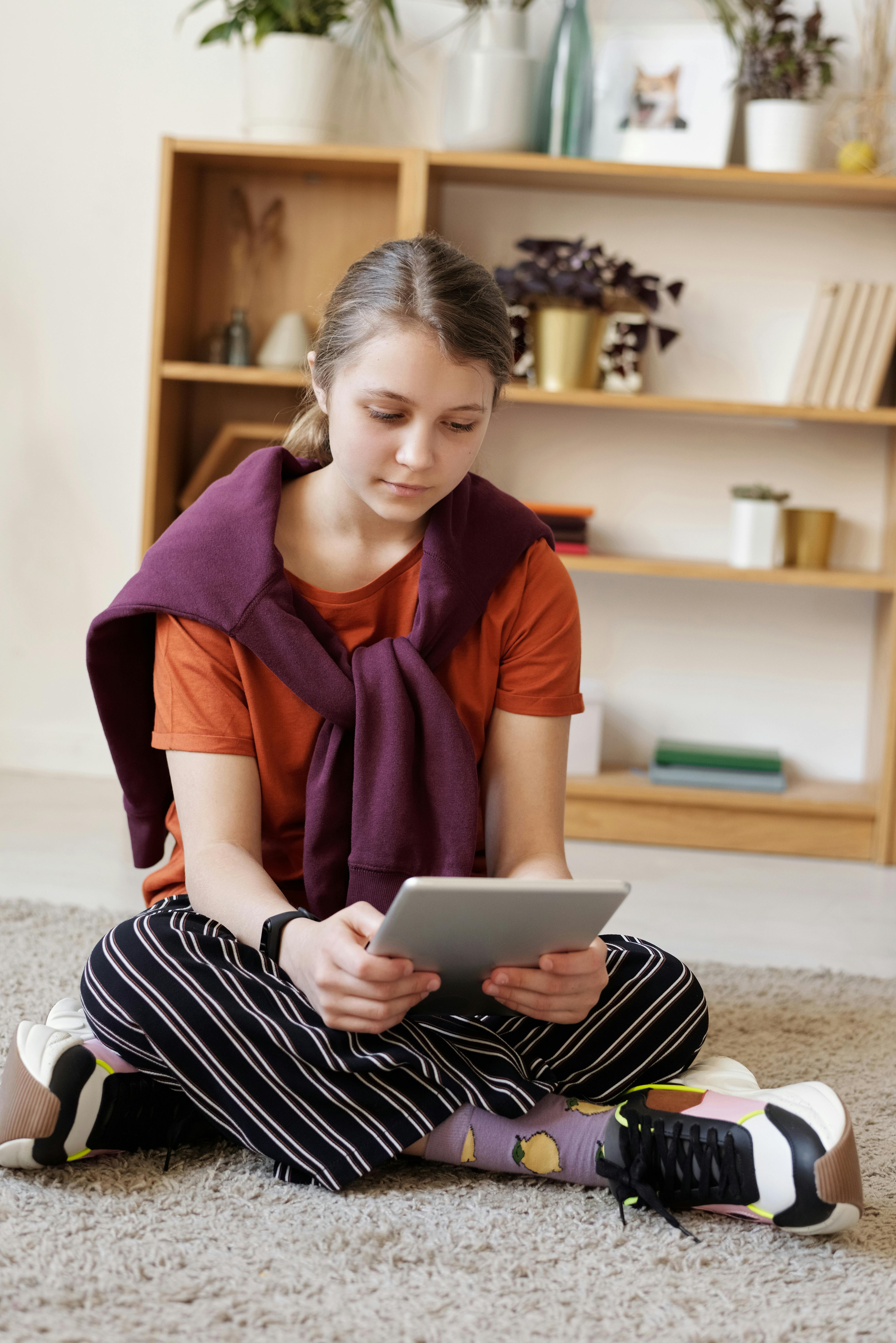 Une adolescente assise par terre utilisant une tablette | Source : Pexels