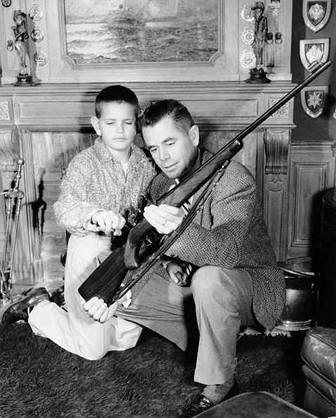 Glenn Ford montrant un fusil a son fils Peter Ford. | Getty images