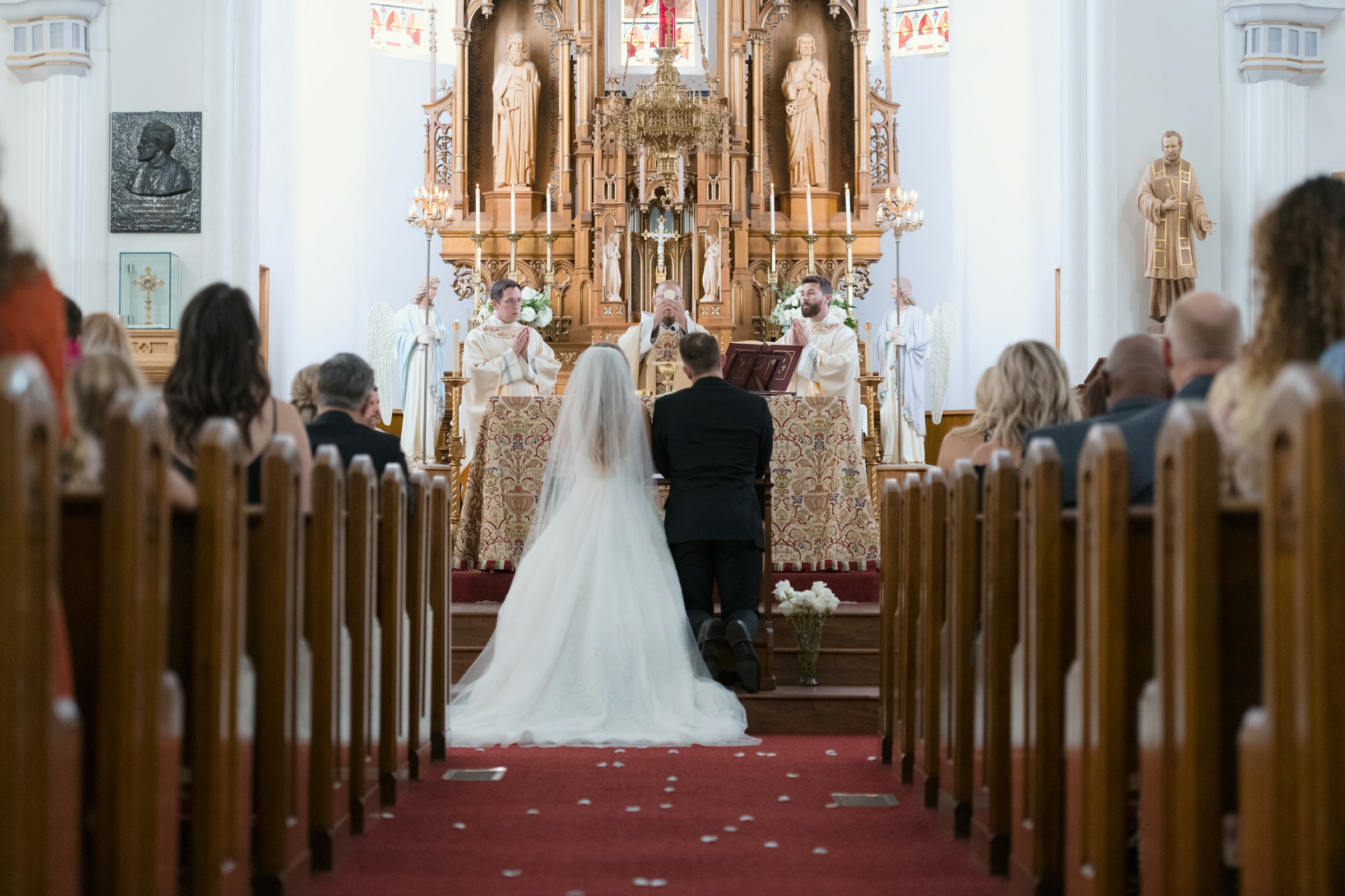 Une mariée et un marié à l'autel lors d'un mariage à l'église pendant que le prêtre élève le Saint Sacrement | Source : Unsplash