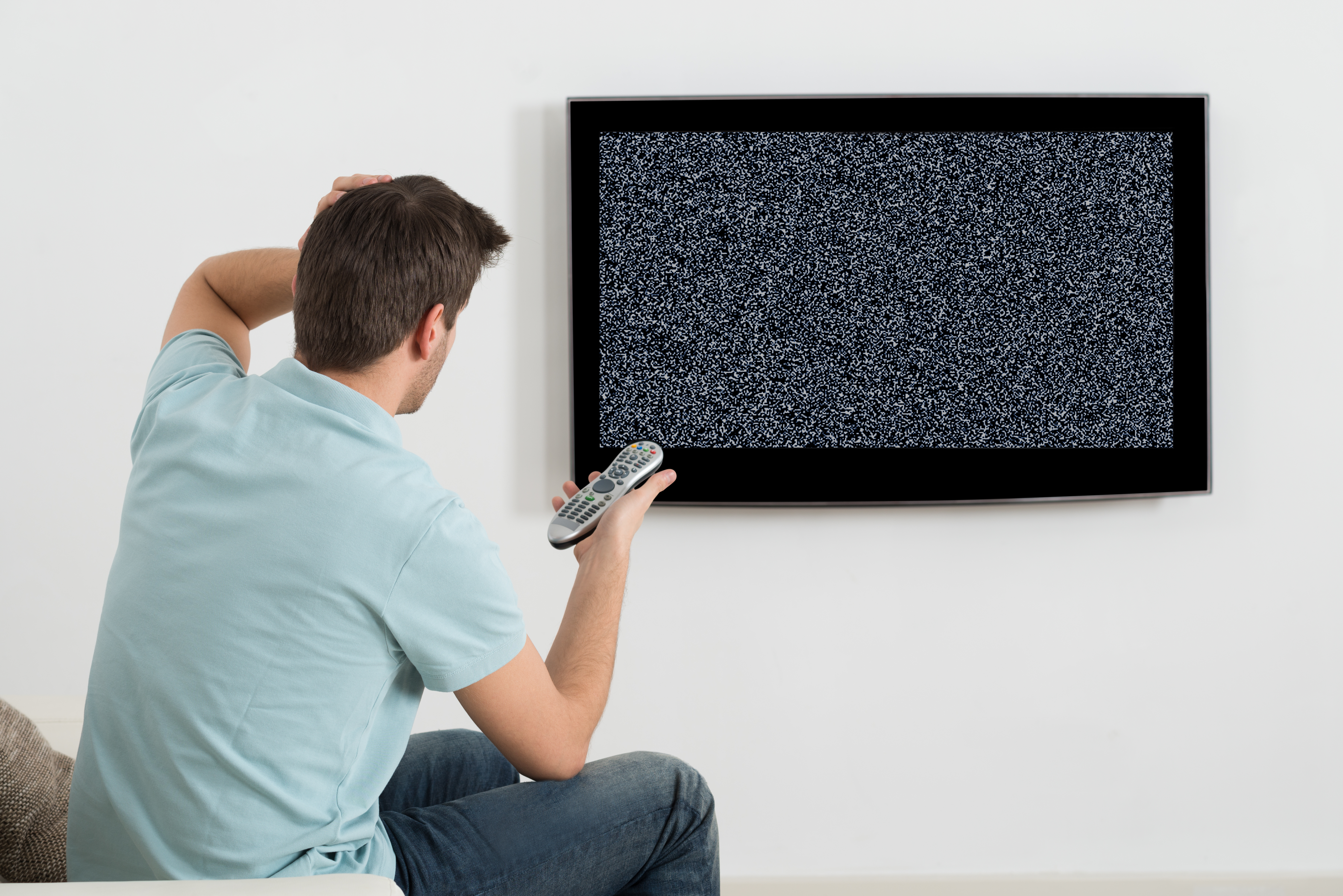 Un homme confus essayant d'allumer un téléviseur | Source : Shutterstock