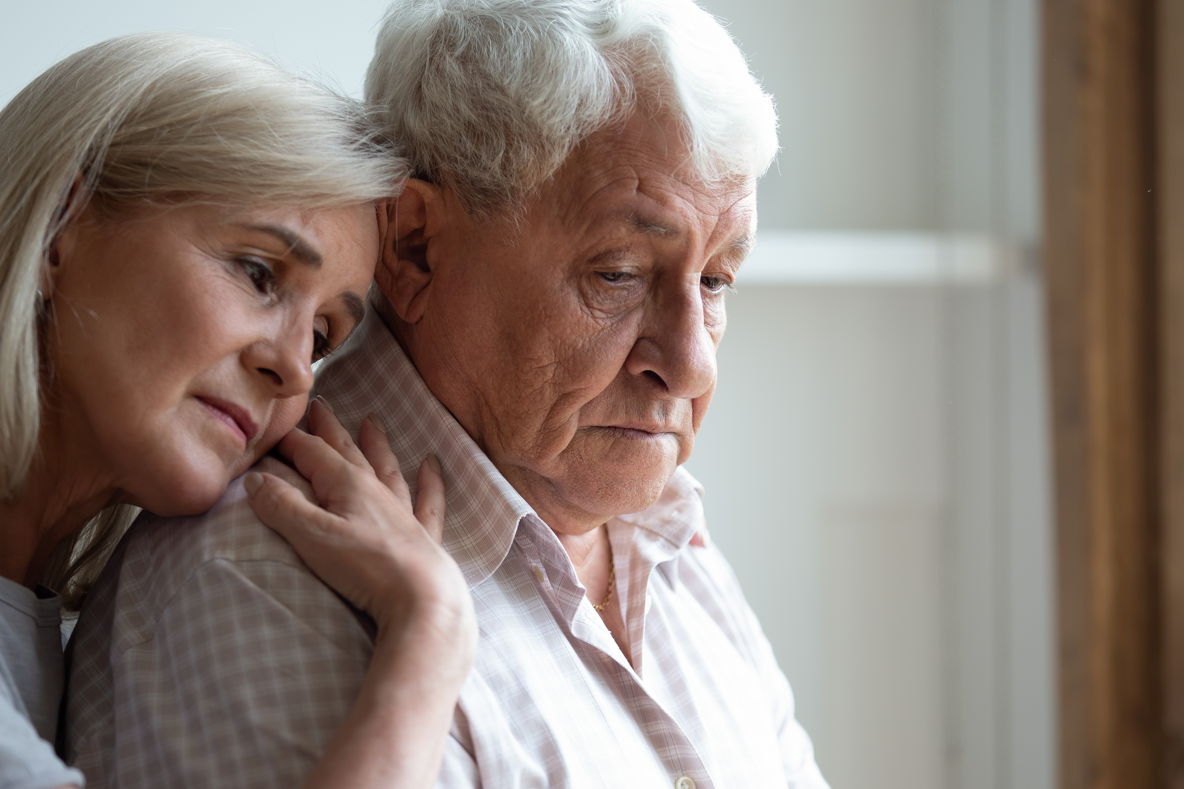 Une femme plus âgée embrasse et réconforte un homme plus âgé qui semble bouleversé | Source : Shutterstock