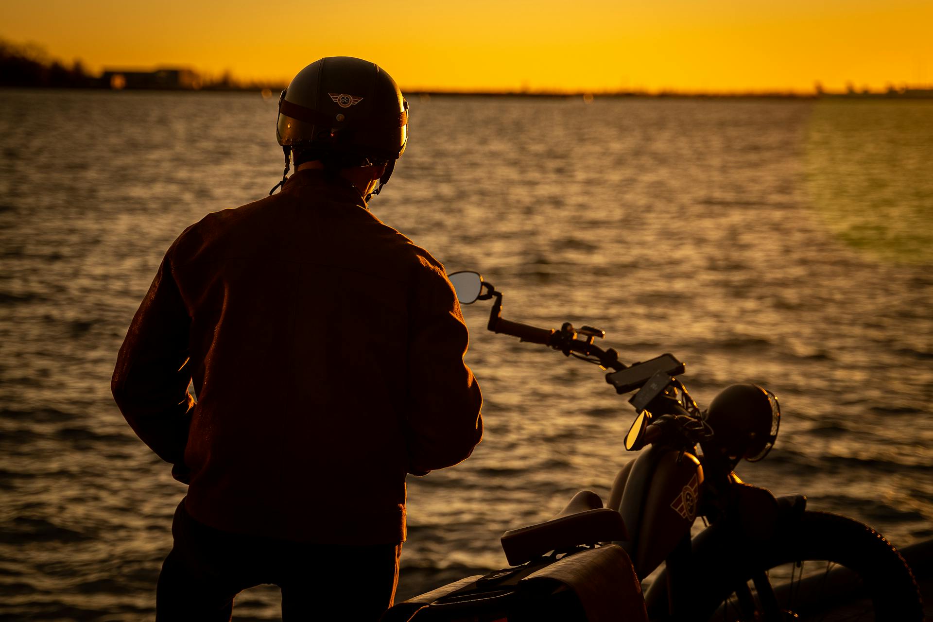 Silhouette of a man standing on the shore near his bicycle | Source: Pexels