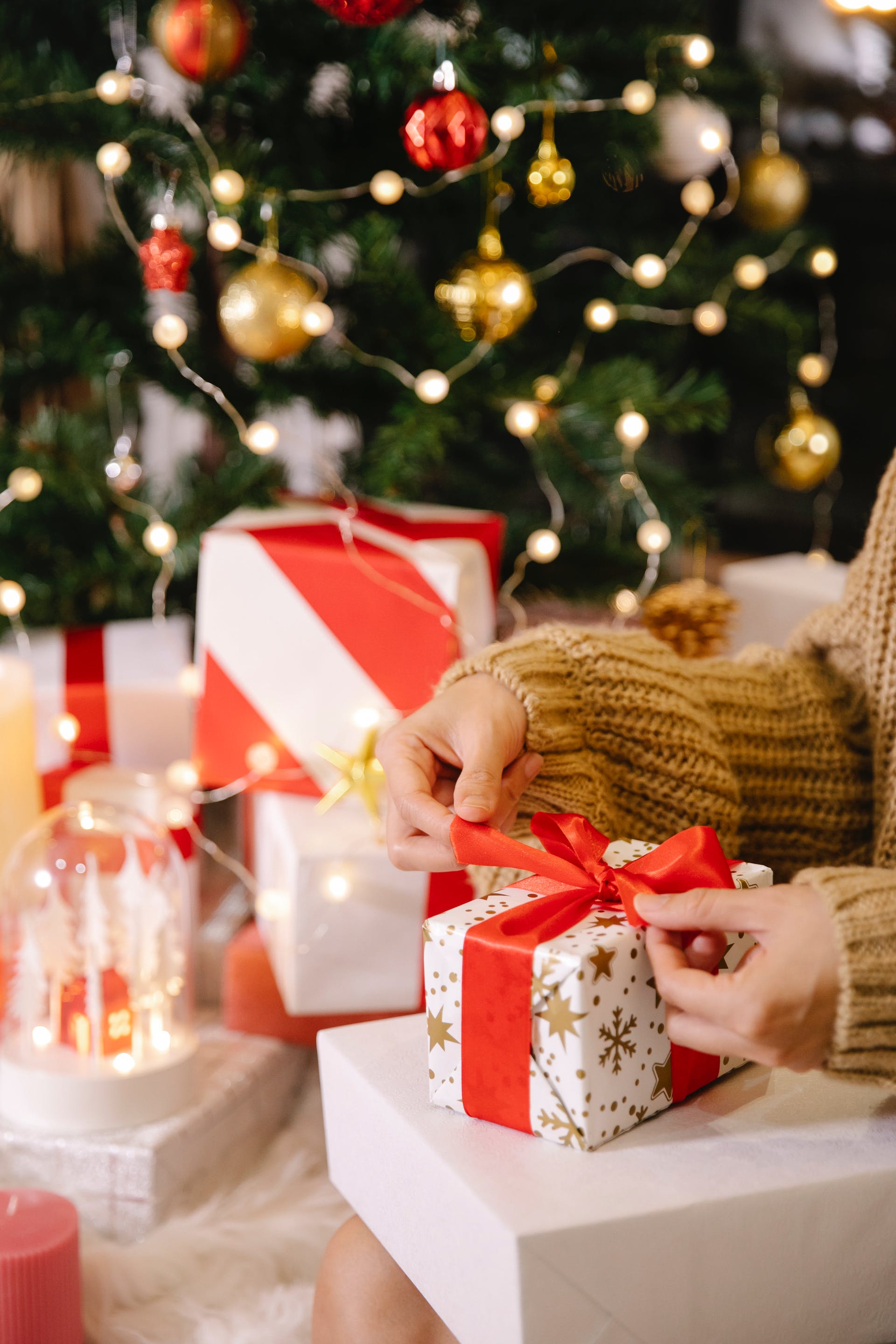 Femme emballant un paquet cadeau près d'un sapin de Noël | Source : Pexels