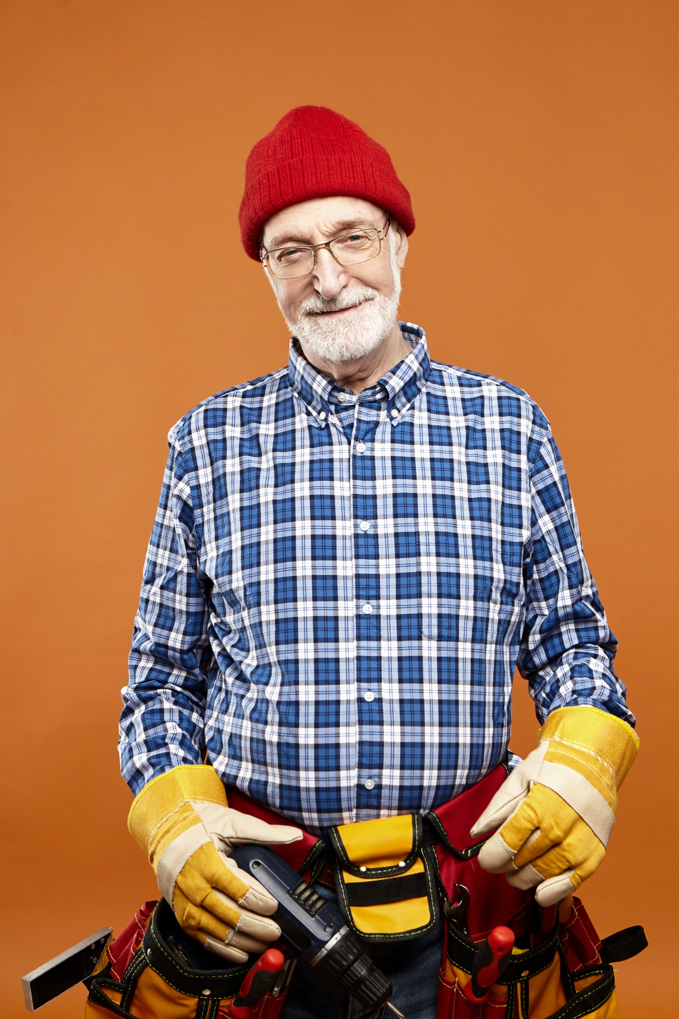 Un homme heureux d'âge moyen portant une ceinture à outils et tenant des outils | Source : Freepik