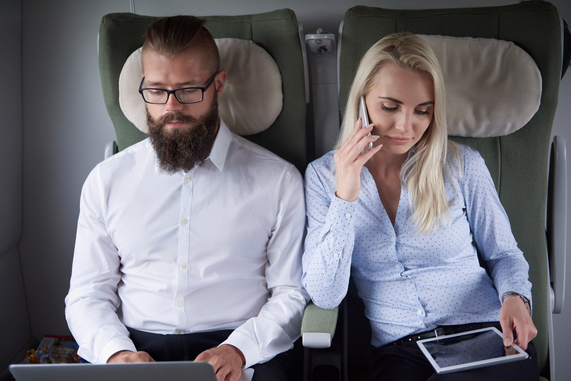 Une femme au téléphone assise à côté d'un homme dans un avion | Source : Freepik
