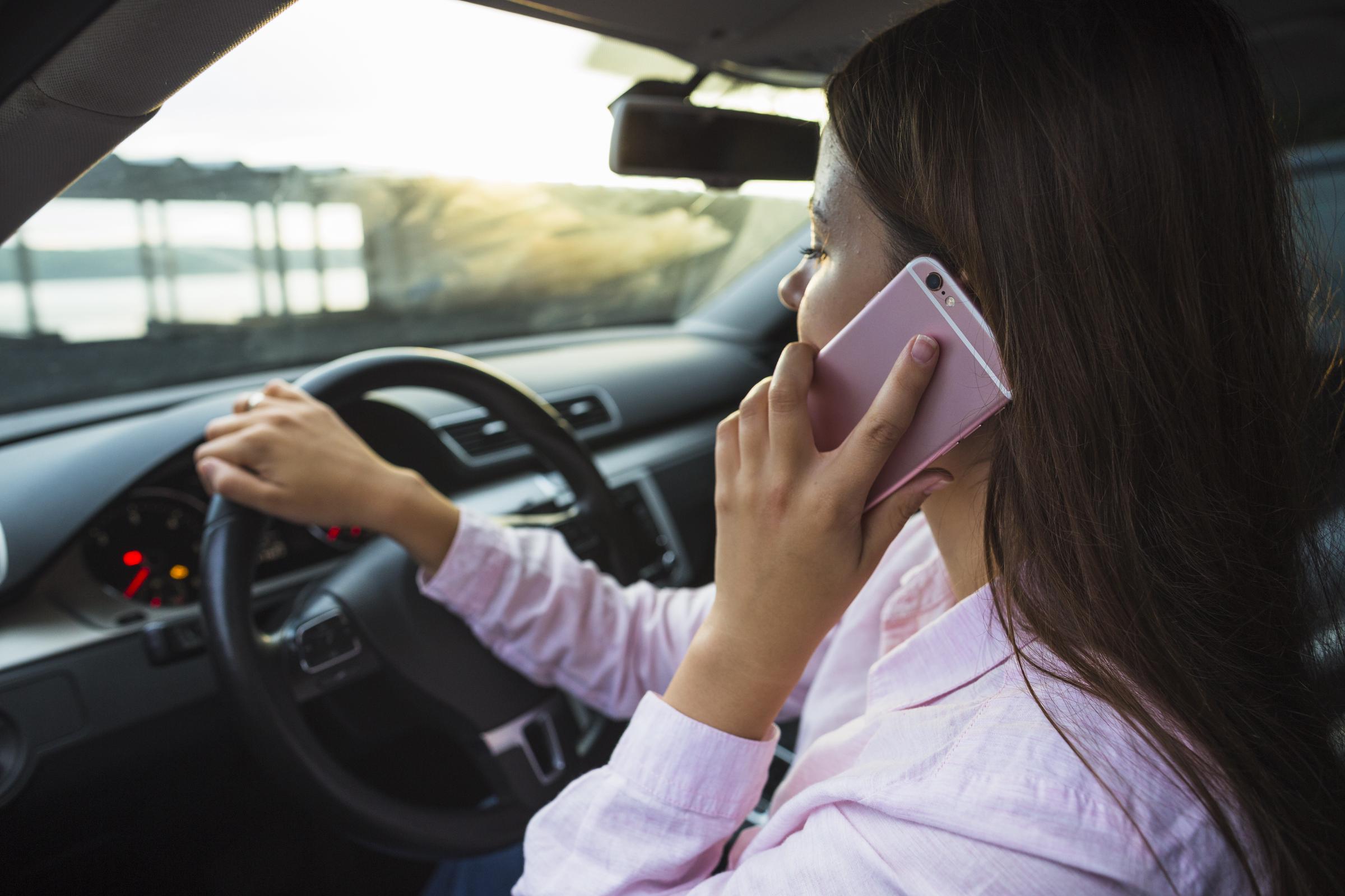 Une femme assise dans sa voiture et parlant au téléphone | Source : Freepik