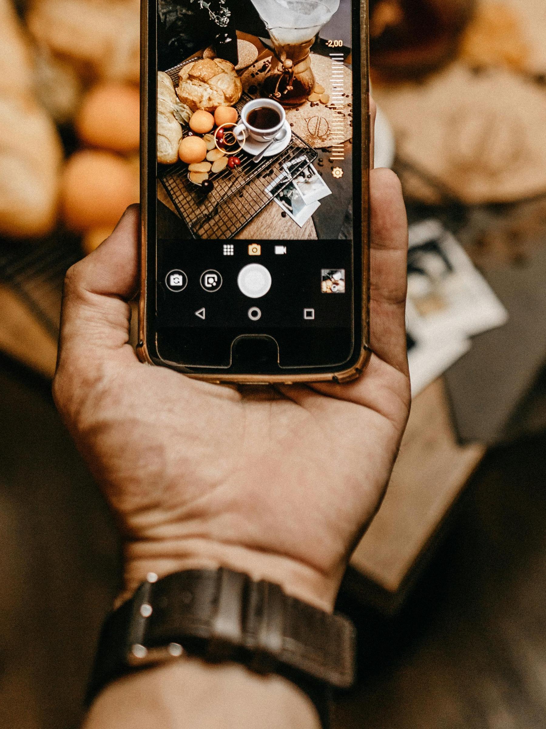 Un homme tient un téléphone portable sur lequel est affichée une photo de préparation d'aliments | Source : Pexels