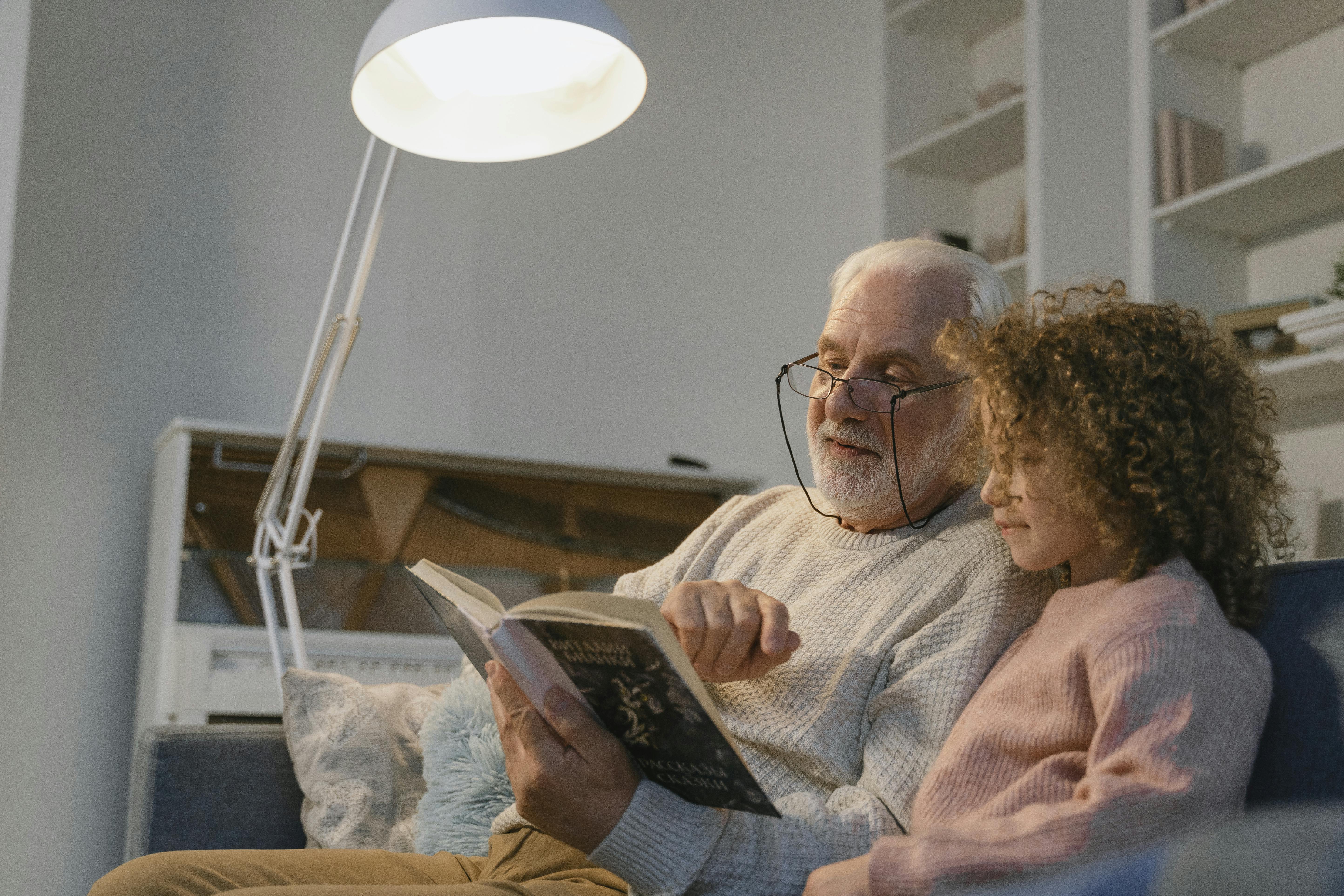 Un grand-père lisant un livre à sa petite-fille | Source : Pexels