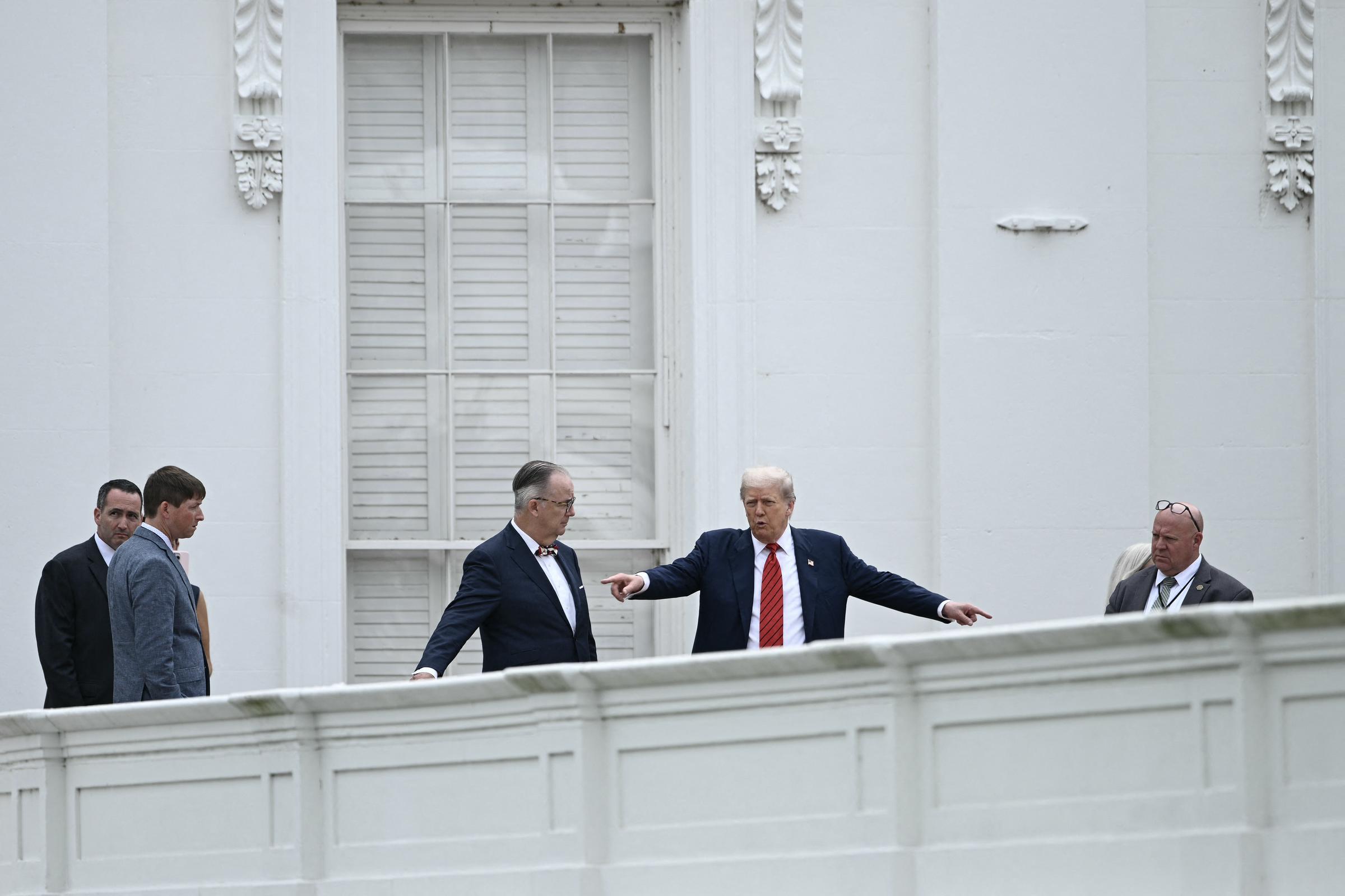 Donald Trump s'entretient avec l'architecte James C. McCrery alors qu'il visite le toit de l'aile ouest de la Maison Blanche à Washington, D.C., soulignant des détails sous le regard des membres de la sécurité et du personnel.