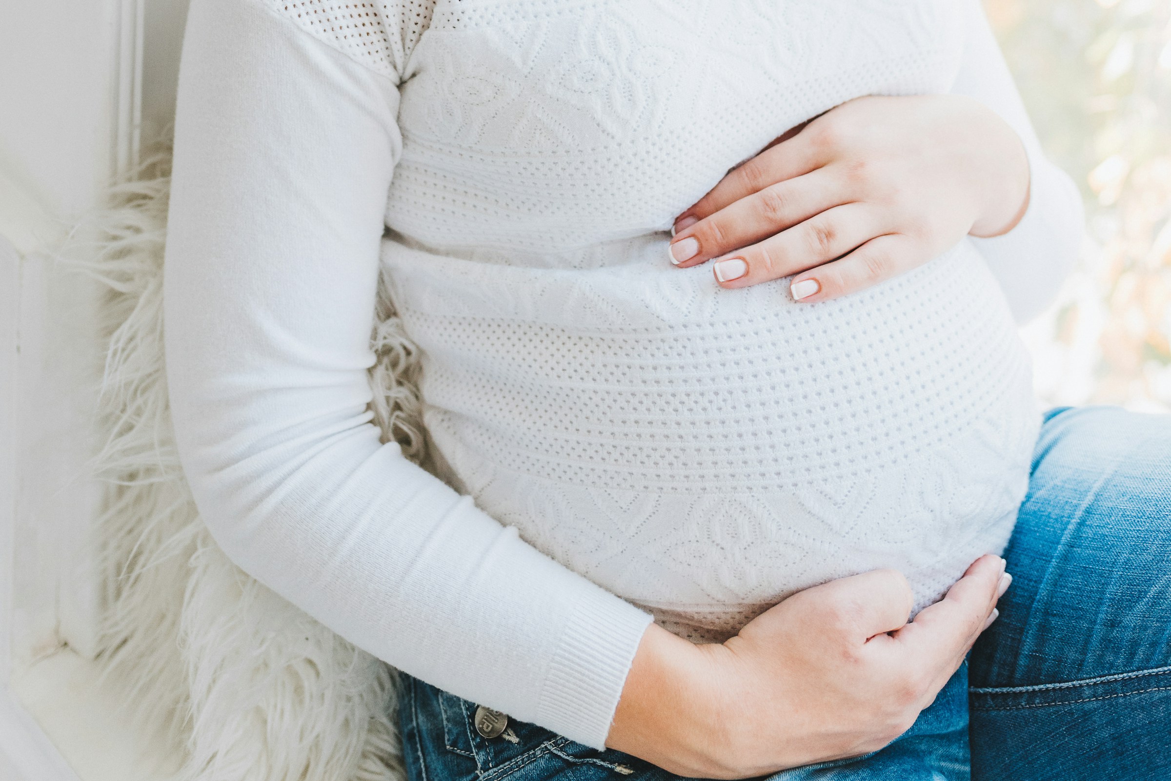 Gros plan d'une femme enceinte tenant son baby bump | Source : Unsplash