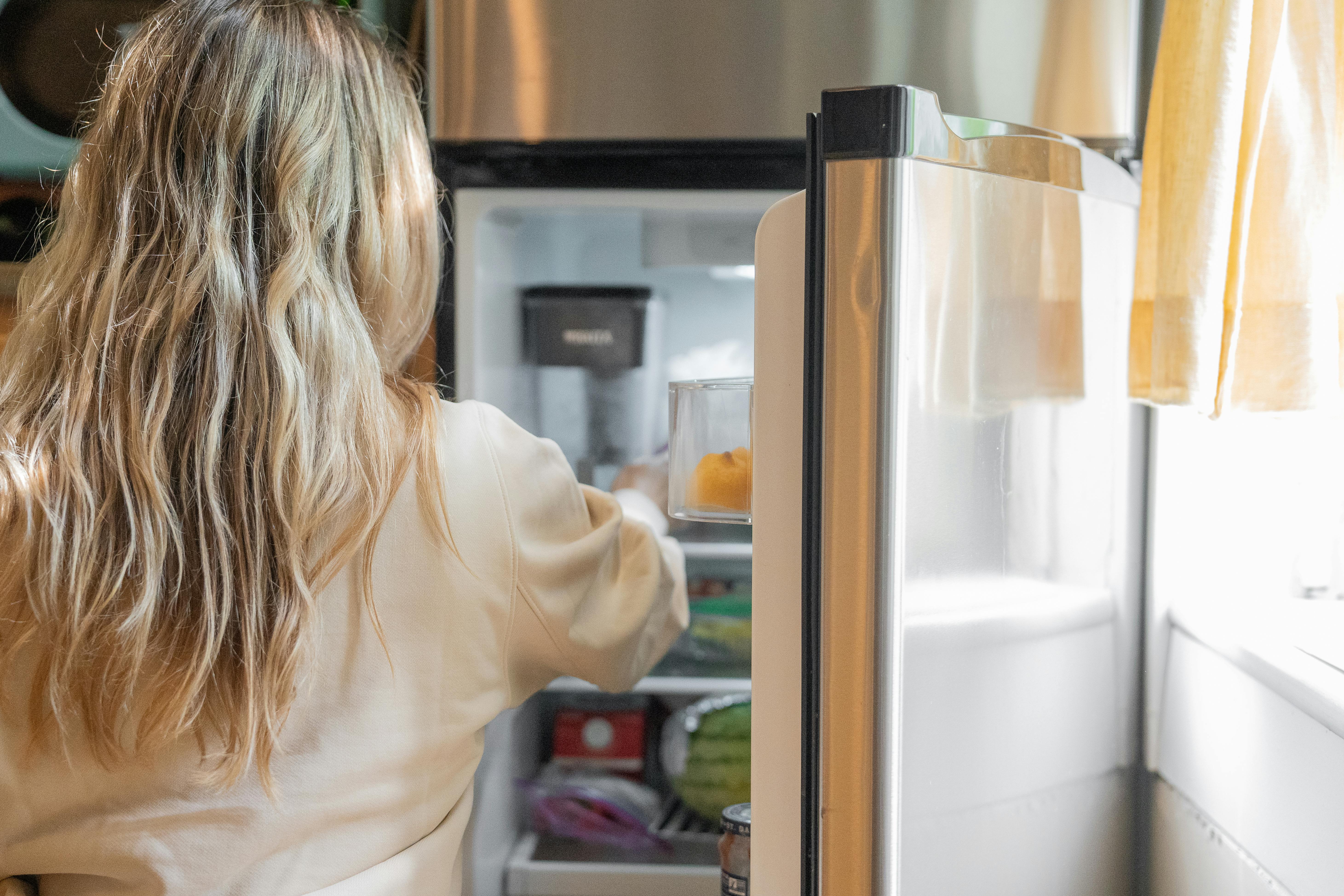 Une femme en train de réapprovisionner le réfrigérateur | Source : Pexels