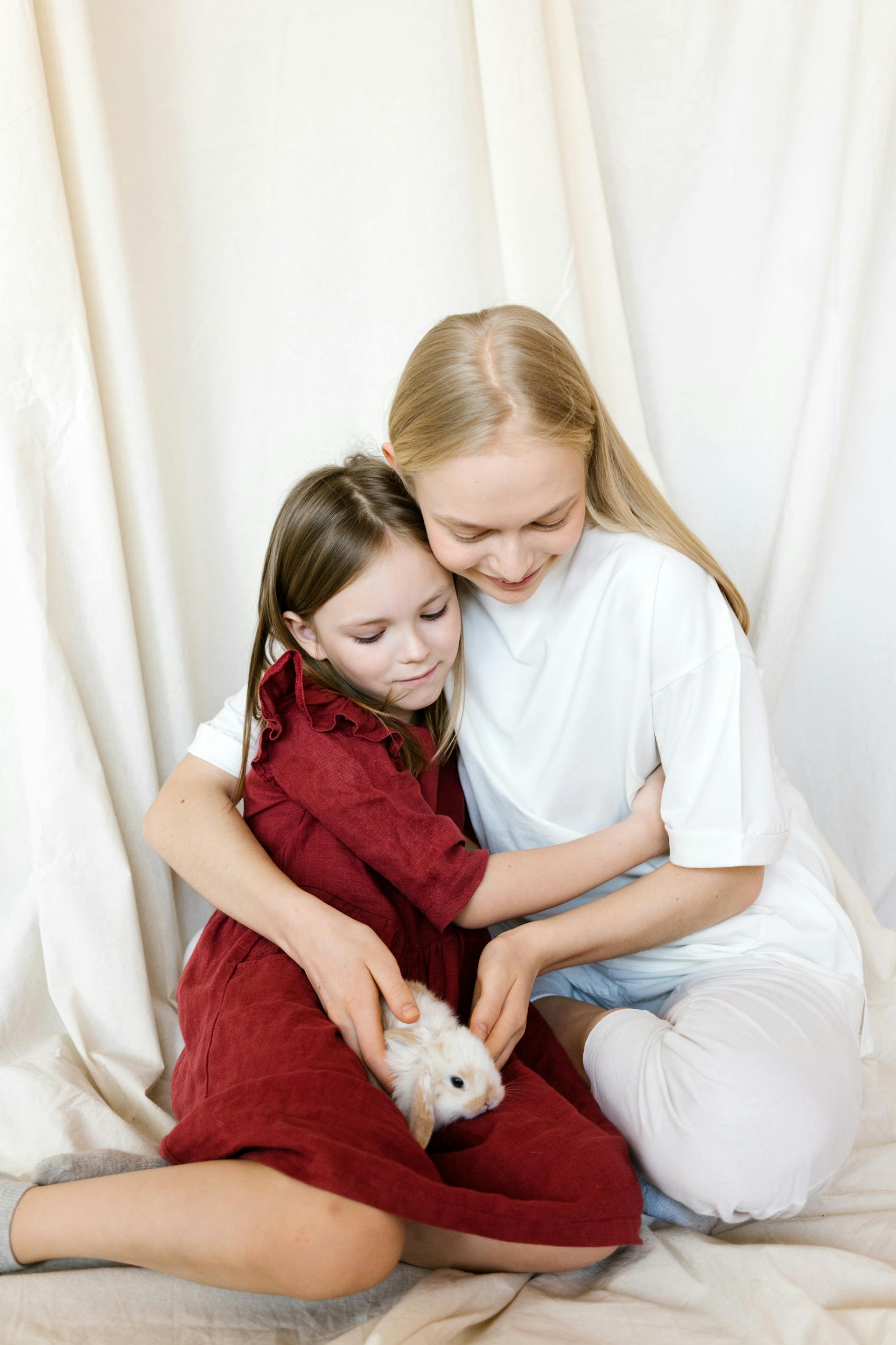 Une jeune fille qui serre sa maman dans ses bras tout en regardant un lapin | Source : Pexels