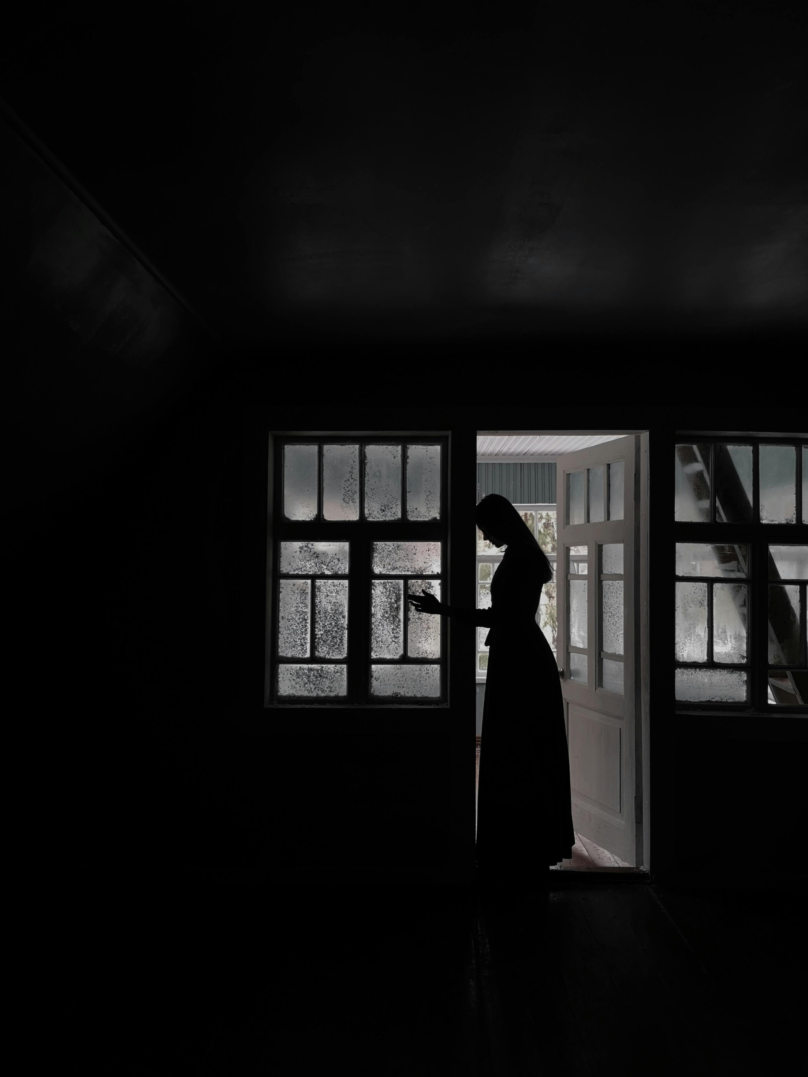 Une femme en robe longue debout dans l'embrasure d'une porte | Source : Pexels