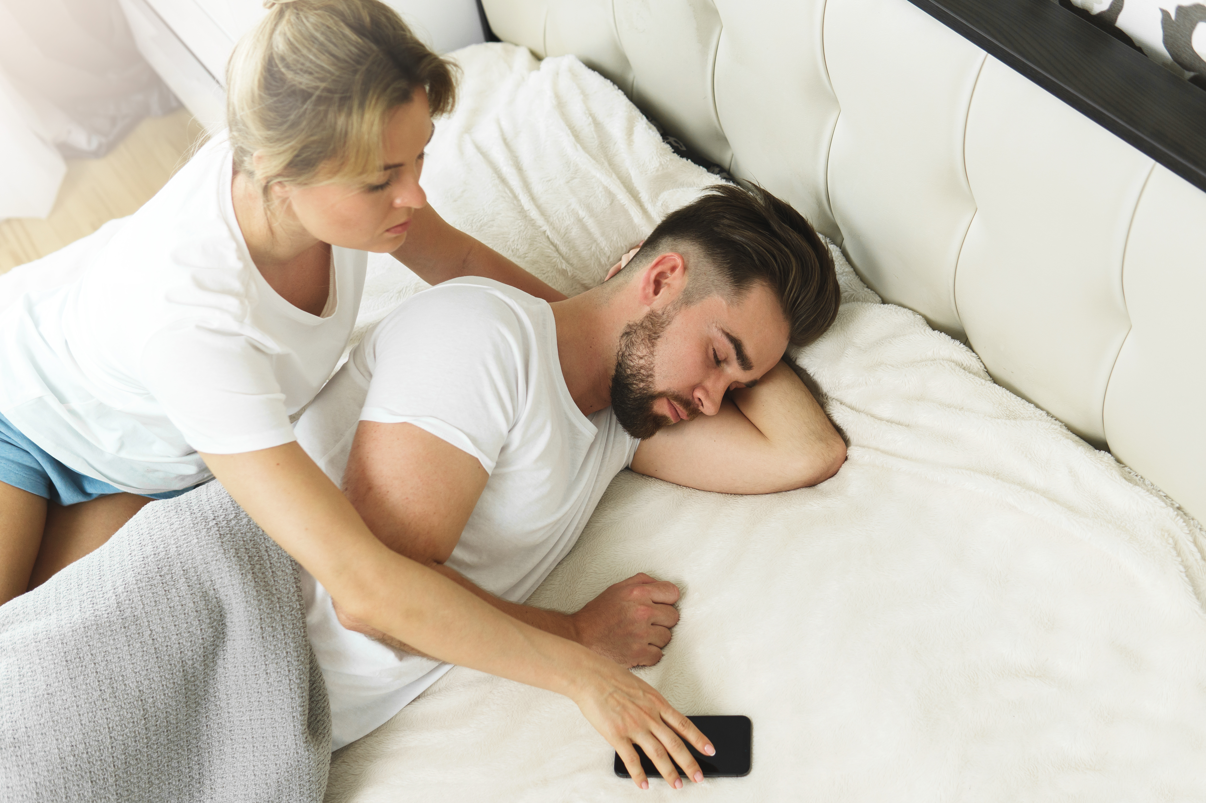 Une femme qui essaie de prendre le téléphone de son partenaire pendant qu'il dort | Source : Shutterstock