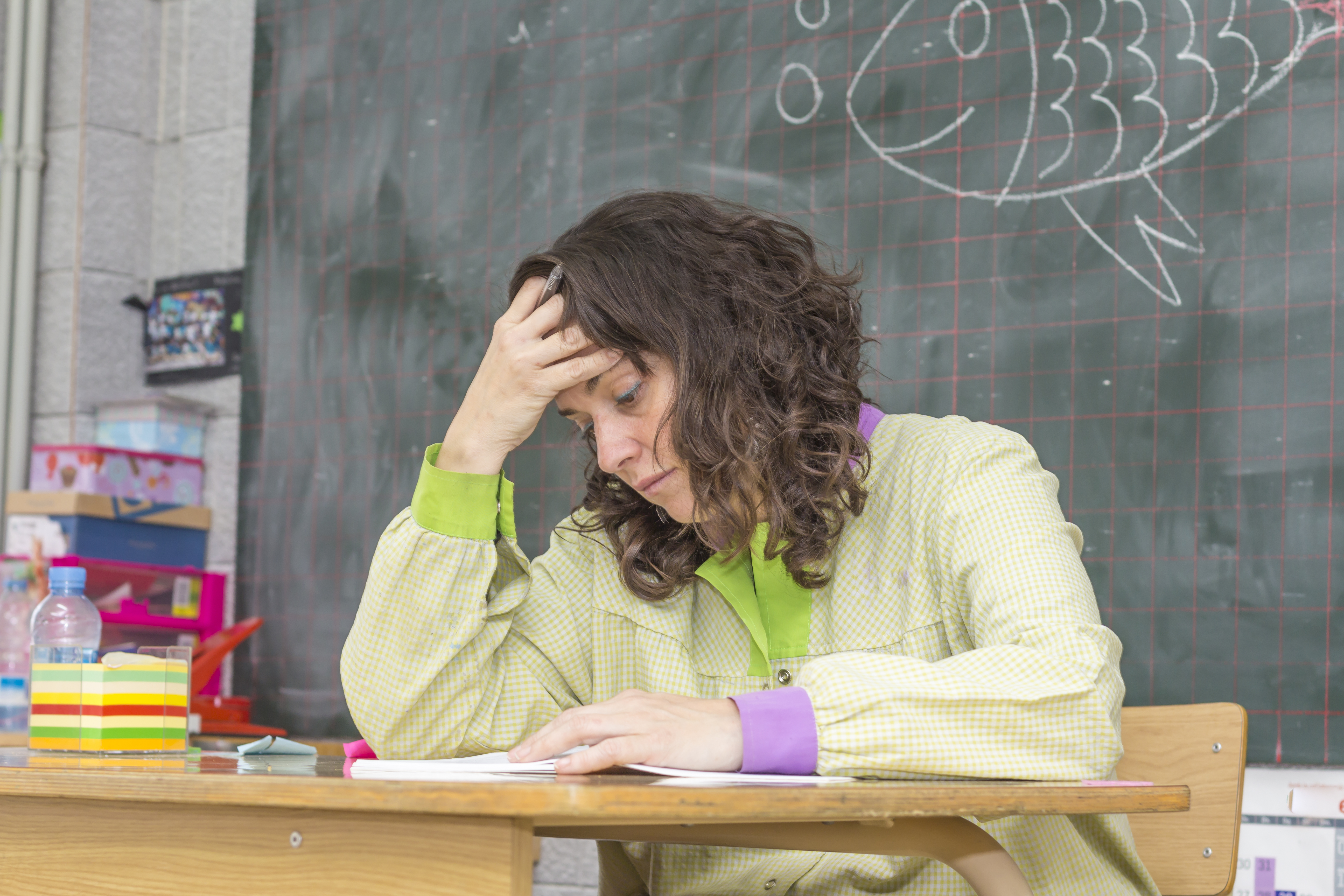 Une enseignante frustrée à son bureau | Source : Shutterstock