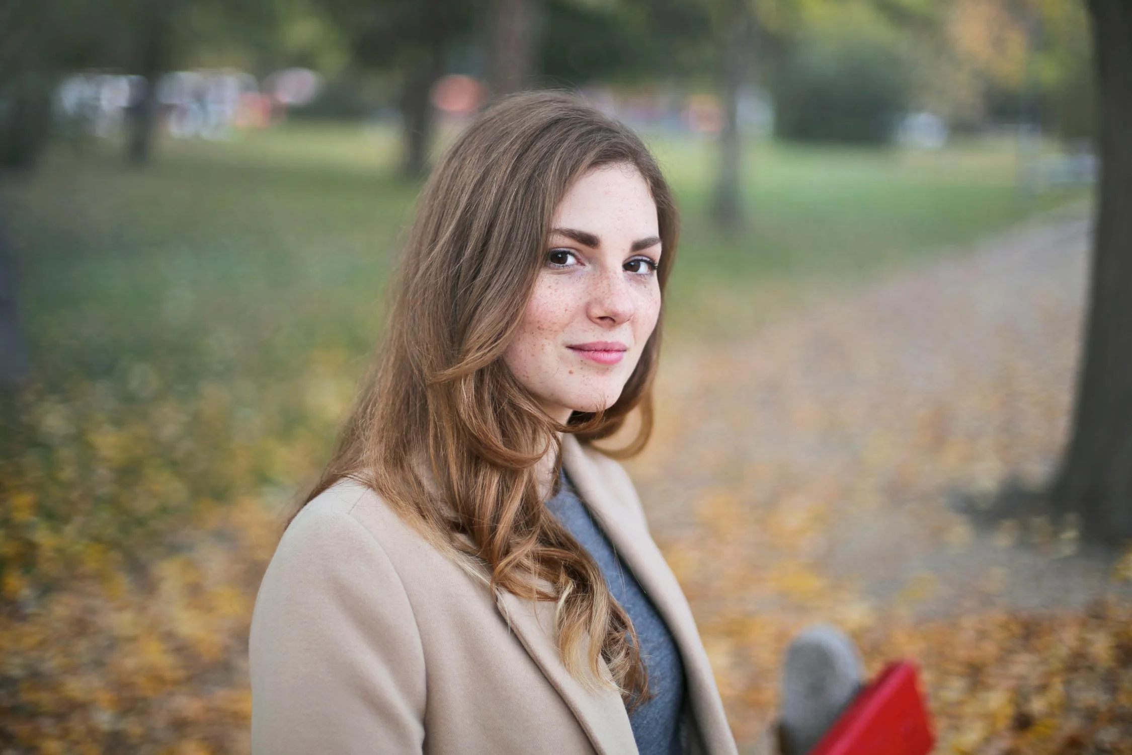 Une jeune femme souriante assise dans un parc | Source : Pexels