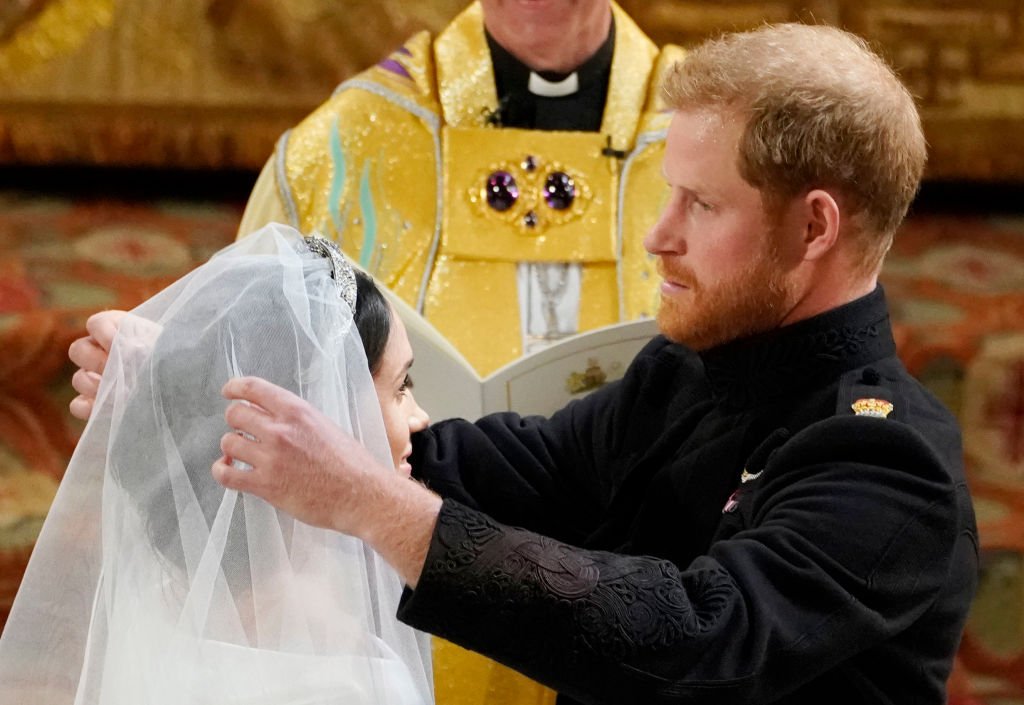 Le prince Harry soulève le voile de Meghan Markle lors de leur cérémonie de mariage en 2018 à la chapelle Saint-Georges du château de Windsor, à Windsor, en Angleterre. | Photo : Getty Images